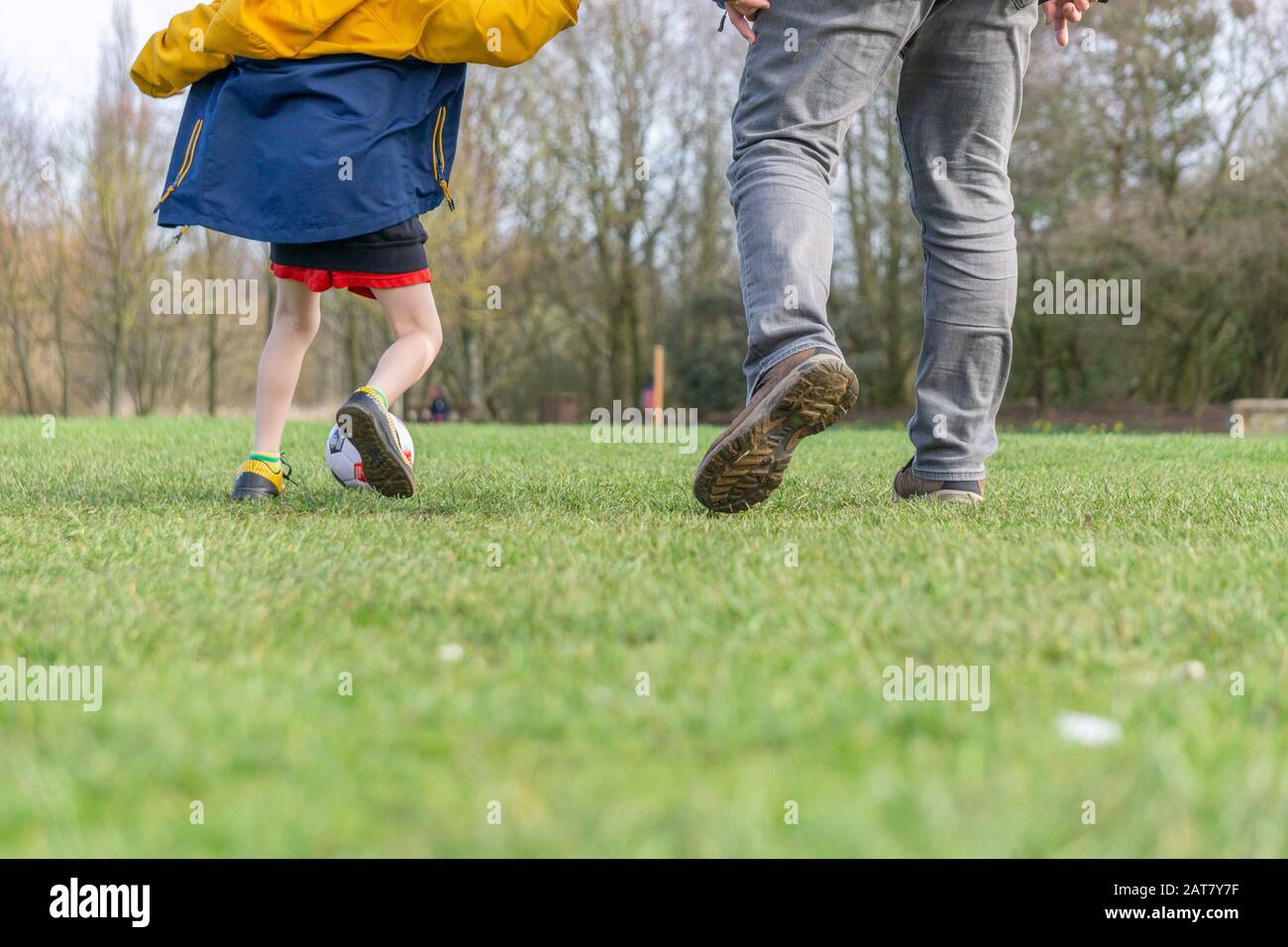 Father and son enjoy a game of football in the park. Stock Photo