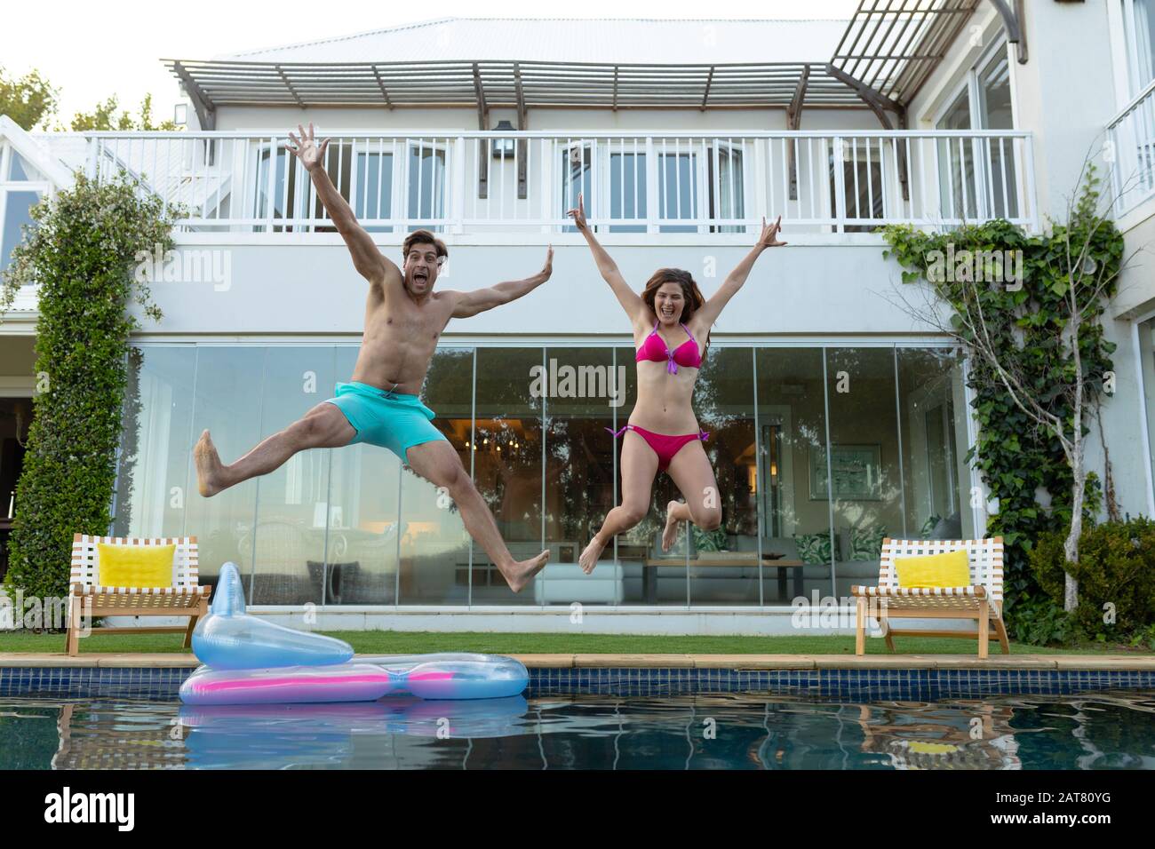 Happy young couple jumping in the swimming pool Stock Photo