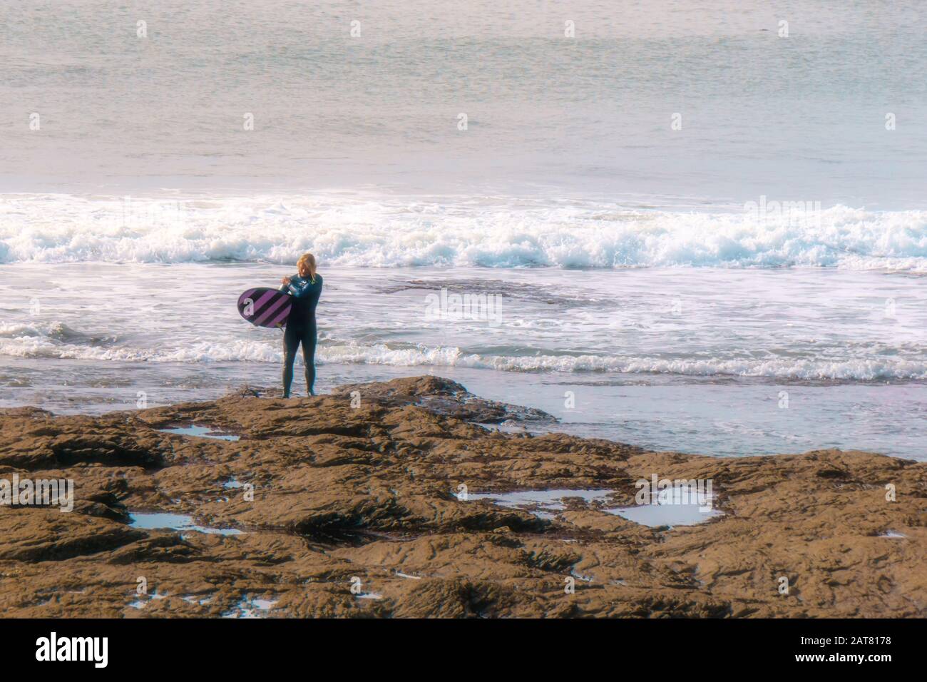 Surfer getting out of the water at Porthleven, Cornwall, October 2019 Stock Photo