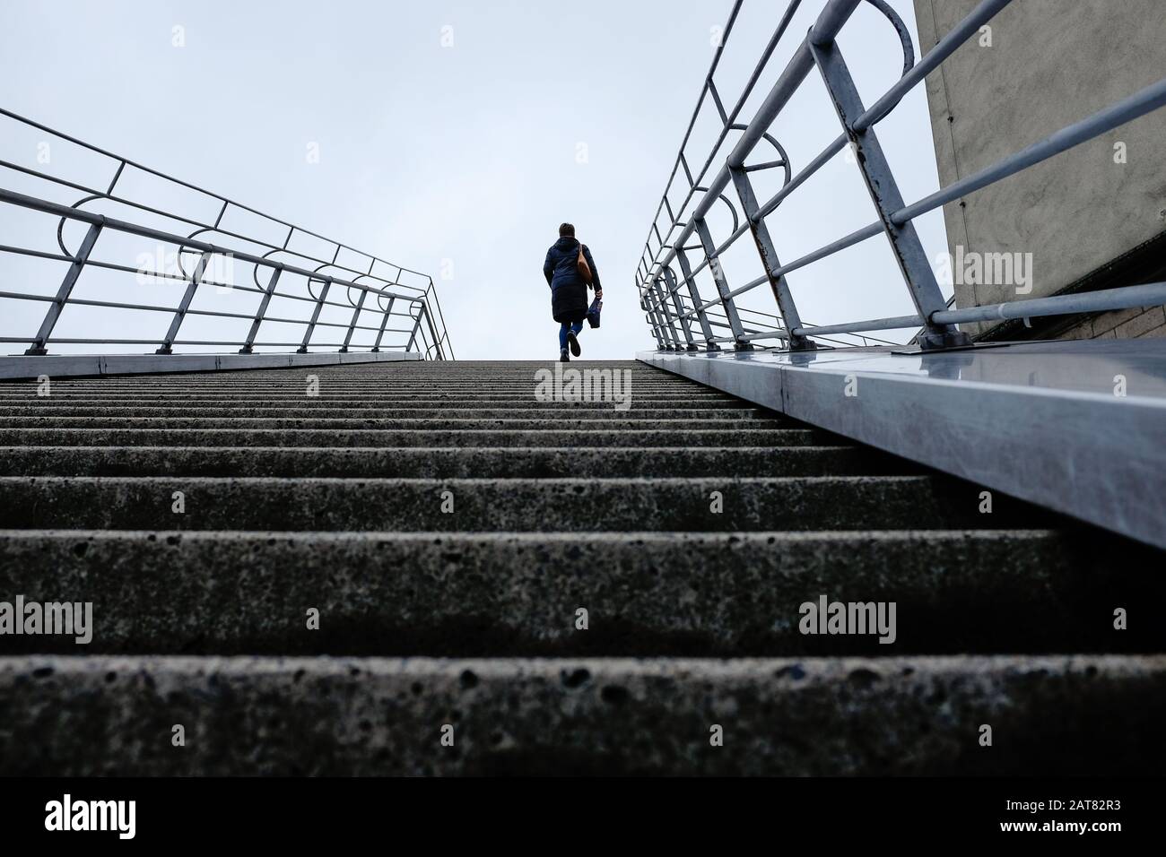 Low angle view of lone figure walking up outdoor steps Stock Photo