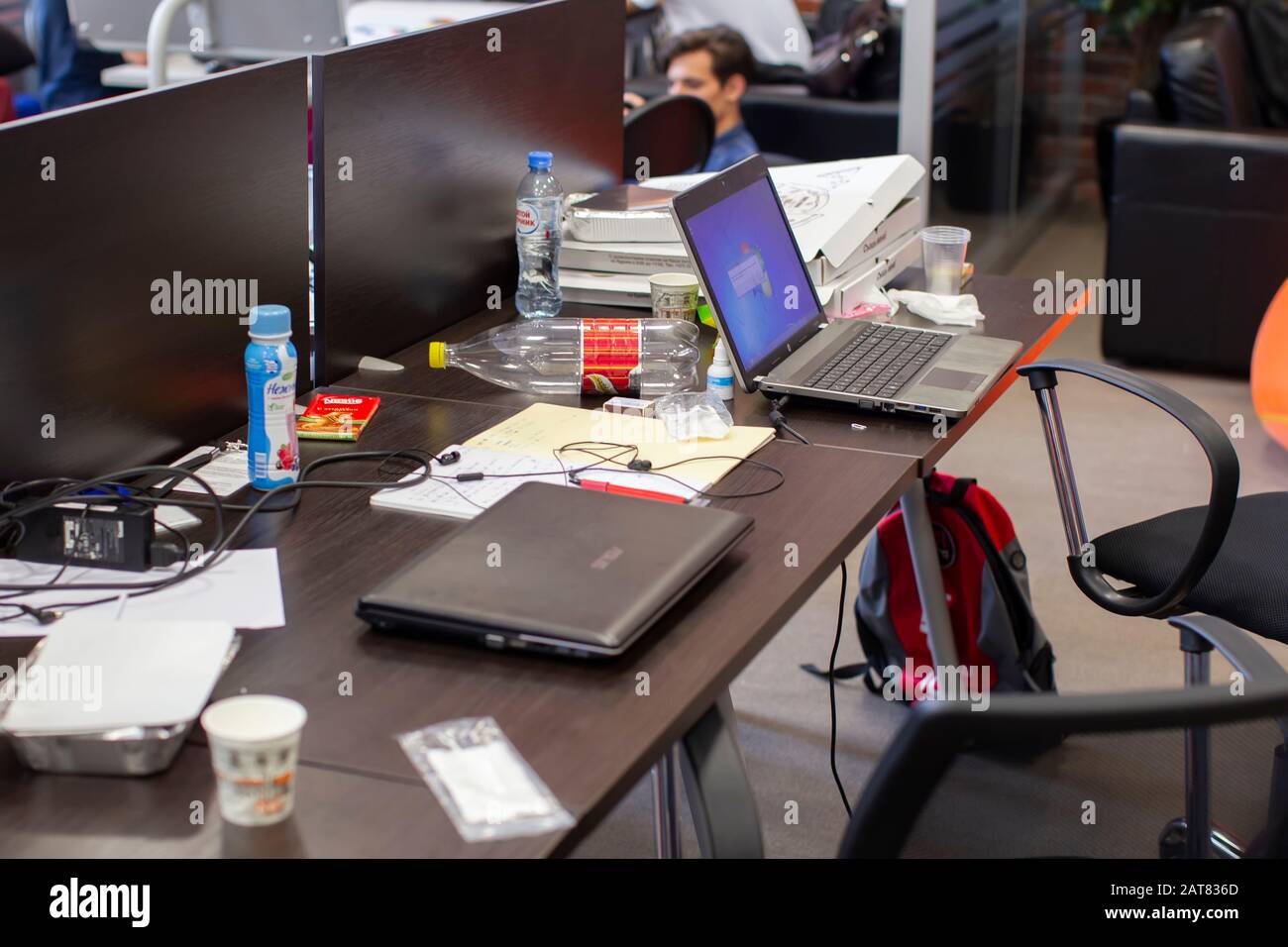 Belarus, the city of Minsk. Programmers Office. Workplace of the programmer.Office desk with laptops cups, leftover food. Stock Photo