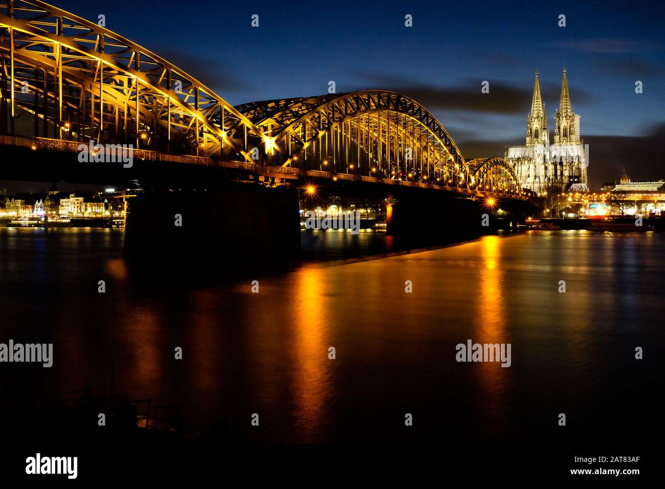 Cologne bridge illuminated at night with cathedral in background Stock Photo