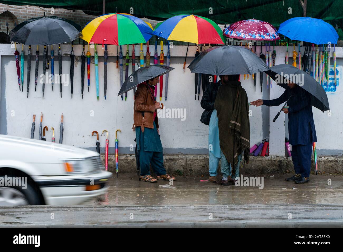 January 29, 2020 - KPK, Pakistan: Local residents purchasing umbrella from a street umbrella seller during rainy weather Stock Photo