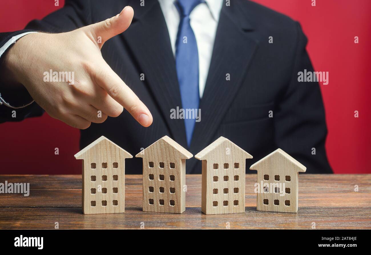 A man chooses a house among others apartment buildings. Housing solution. Best choice of presented options. Purchase of new modern home. Standard of l Stock Photo
