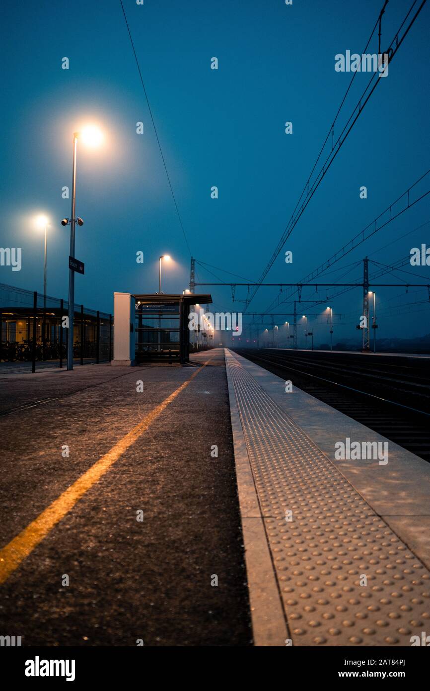 Empty European Railroad Station at Dusk with a One Point Perspective in France with Misty Conditions.Thick fog settles over railroad tracks at night. Stock Photo