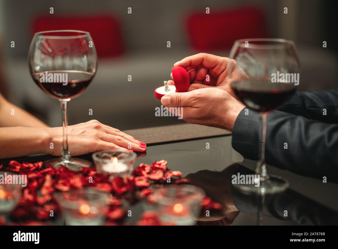 A couple having a romantic dinner and a suprise proposal in a elegance restaurant with beautiful decoration. Romance and Valentines day concept Stock Photo