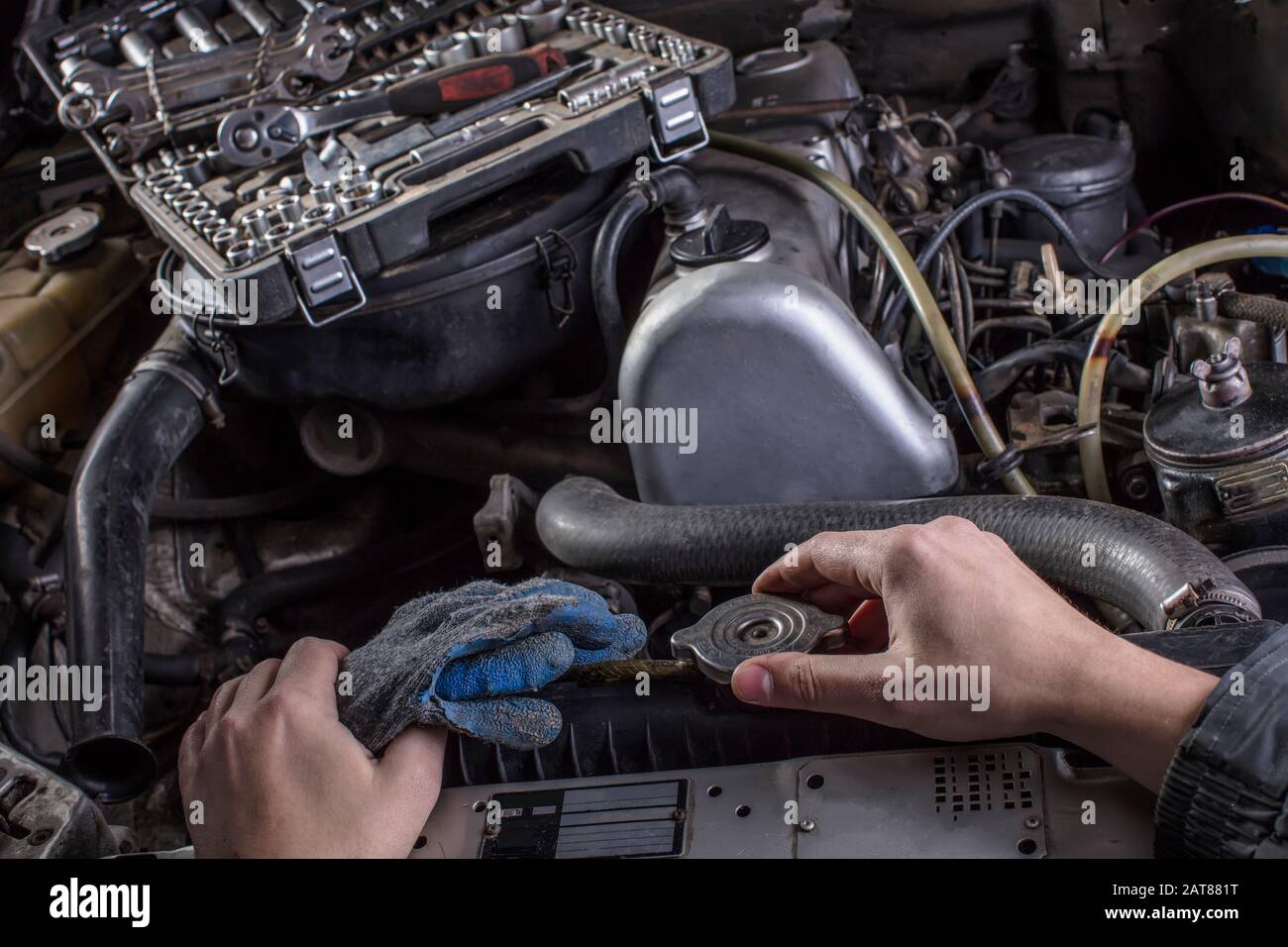 Car engine repair. Engine cooling system services. Hands with a