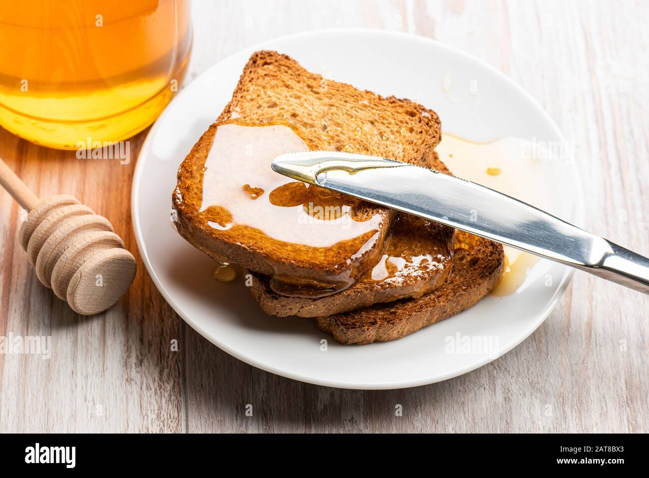 Spread honey on wholemeal rusks with knife. Stock Photo