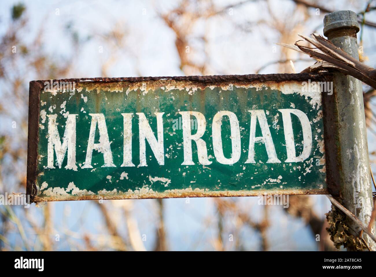 Almost unreadable rusty road signage 'Main Road', with branches and dry leafs hanging around, seen after typhoon Ursula on Boracay in the Philippines Stock Photo