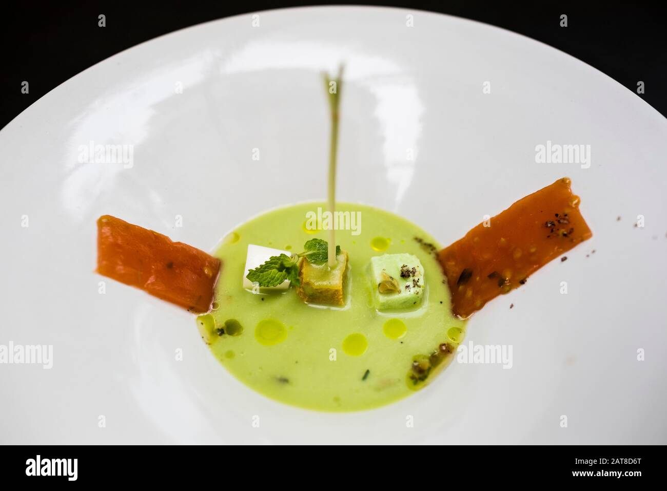 High angle close up of chilled snow pea soup with tomato and herbs. Stock Photo