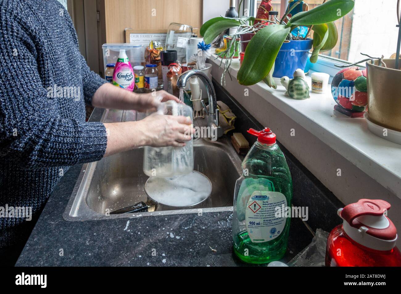 A time lapse of a middle aged man washing up in a kitchen sink. Stock Photo