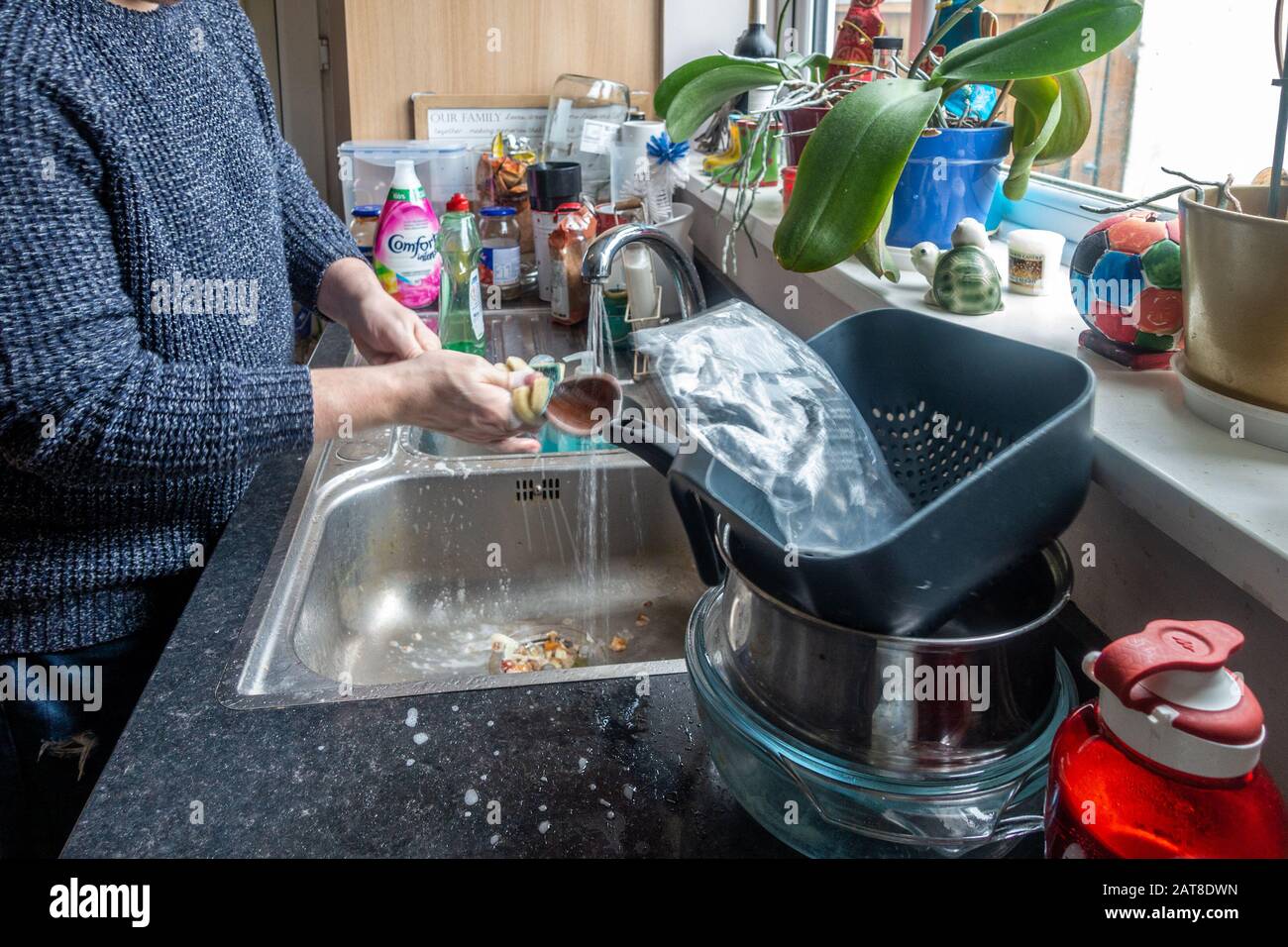 A time lapse of a middle aged man washing up in a kitchen sink. Stock Photo