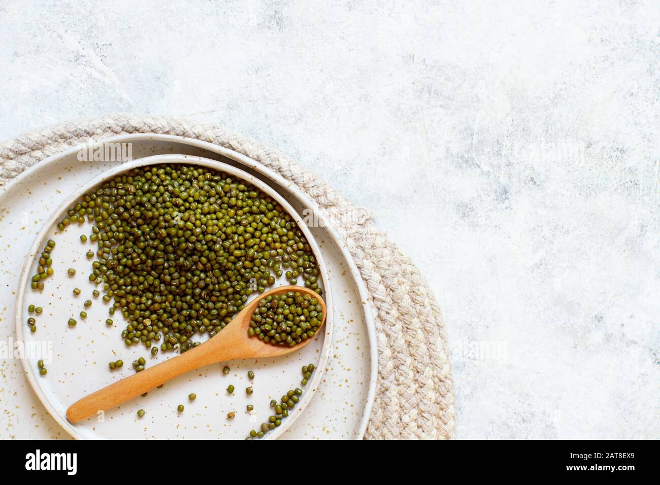 Dried mung beans on a plate with a spoon on a white table top view Stock Photo