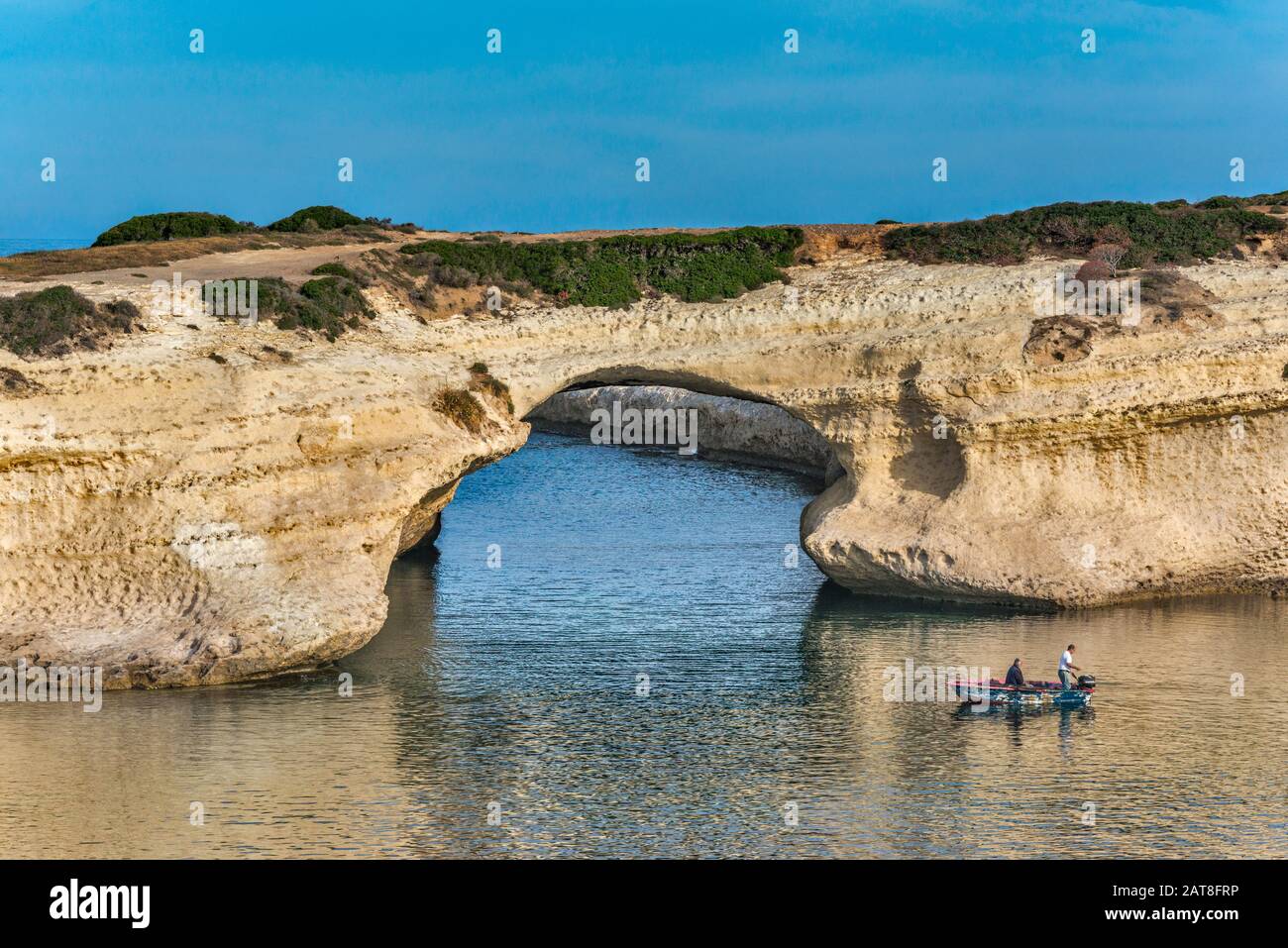 Men fishing at Arco di S'Archittu, natural arch near Spiaggia dell'Arco, beach in S'Archittu, municipality of Cuglieri, Sardinia, Italy Stock Photo