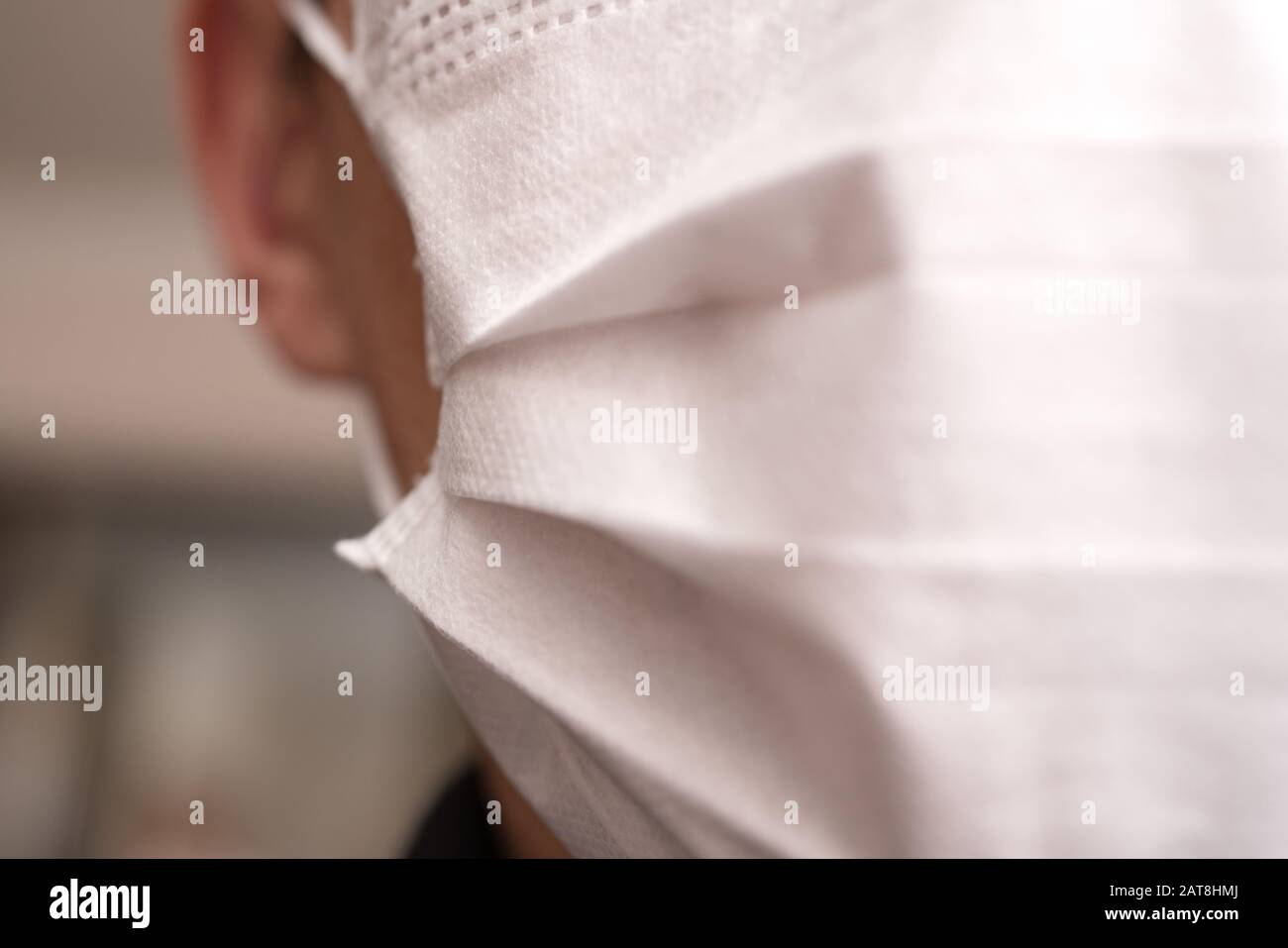 Closeup with the face of a young man wearing medical or surgical mask ...