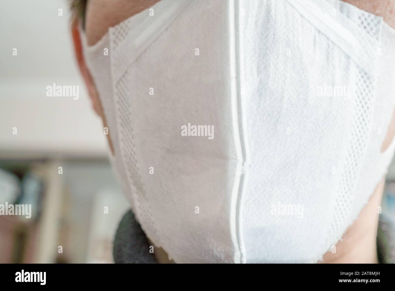 Closeup with the face of a young man wearing medical or surgical mask ...