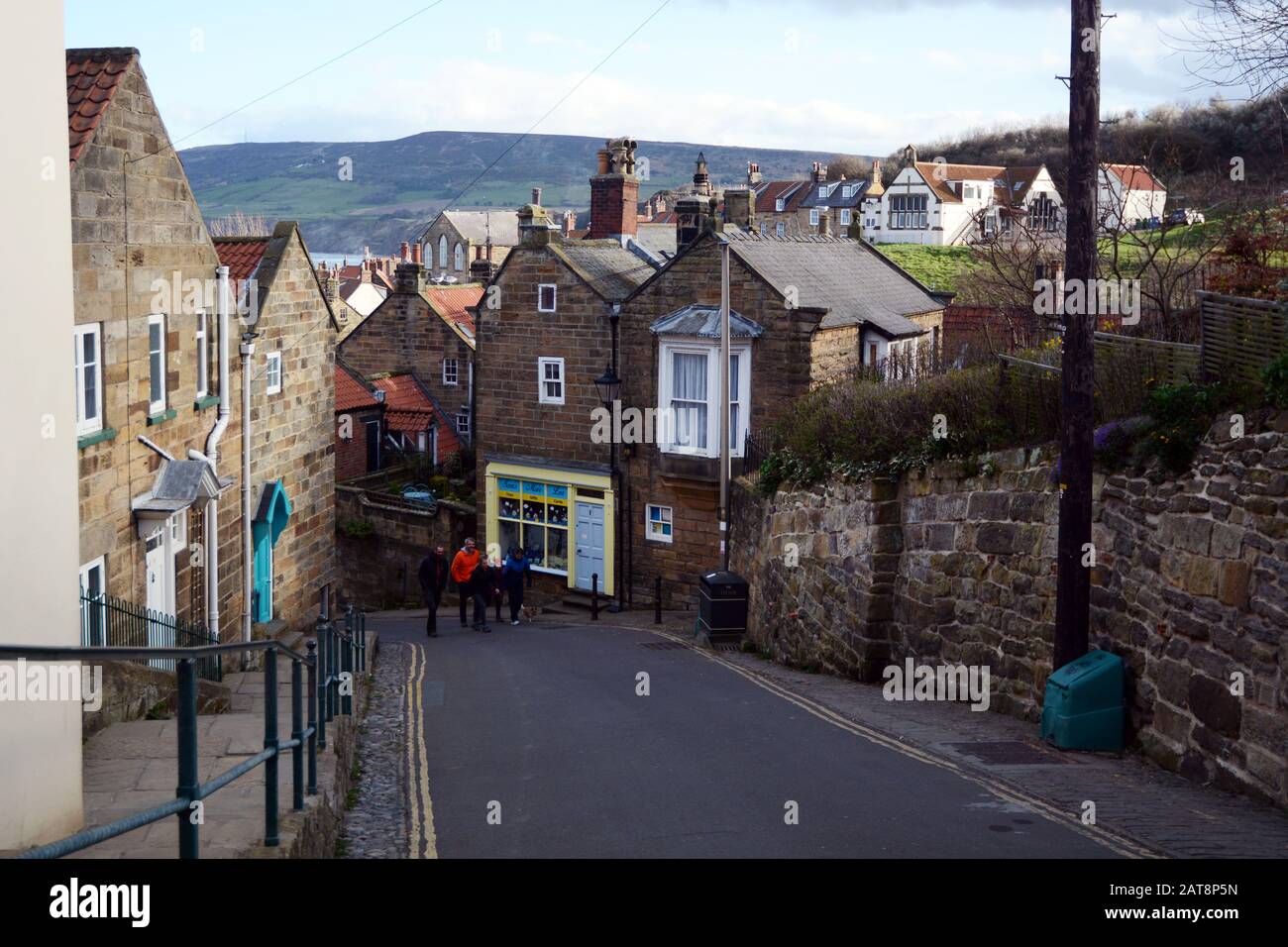Tourists walking along a road in the town of Robin Hood's Bay, North York Moors National Park, Yorkshire, England, United Kingdom. Stock Photo