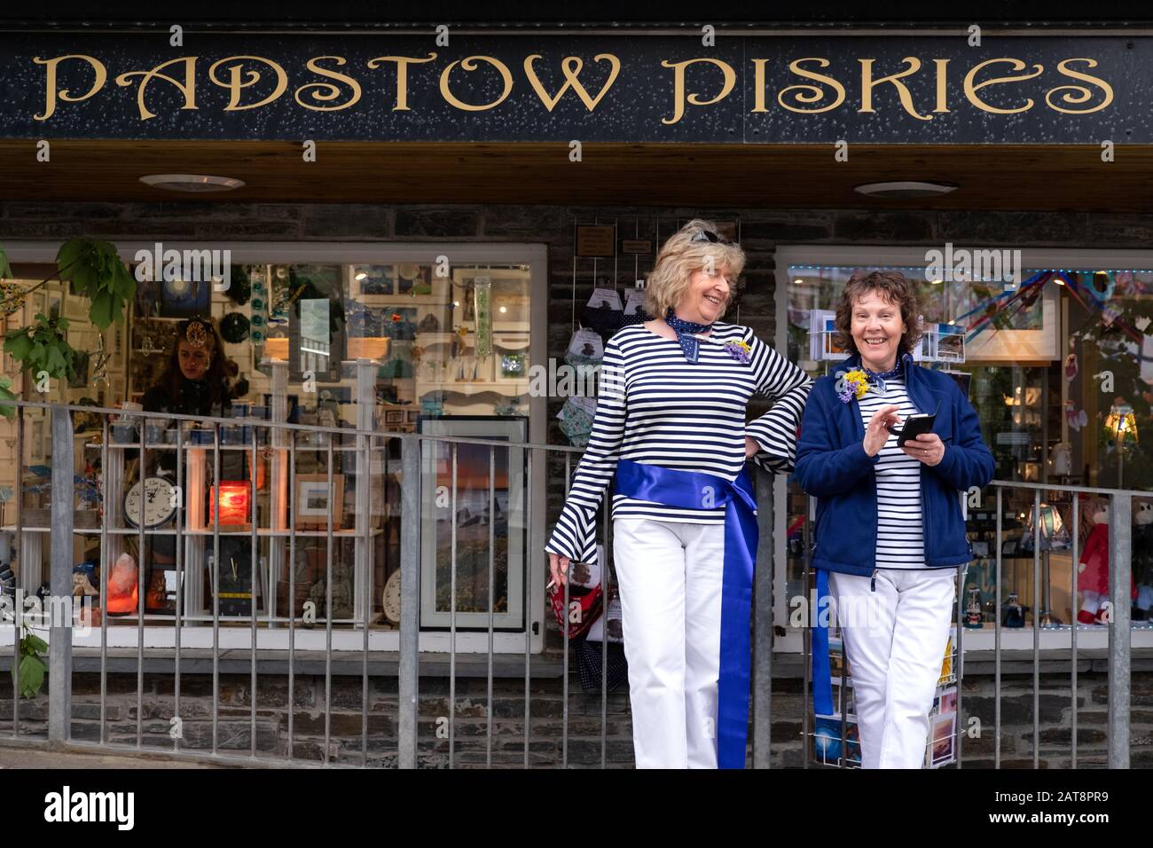 Two women wearing blue ribbons outside Padstow Piskies at he Obby Oss procession, Padstow, Cornwall, UK Stock Photo