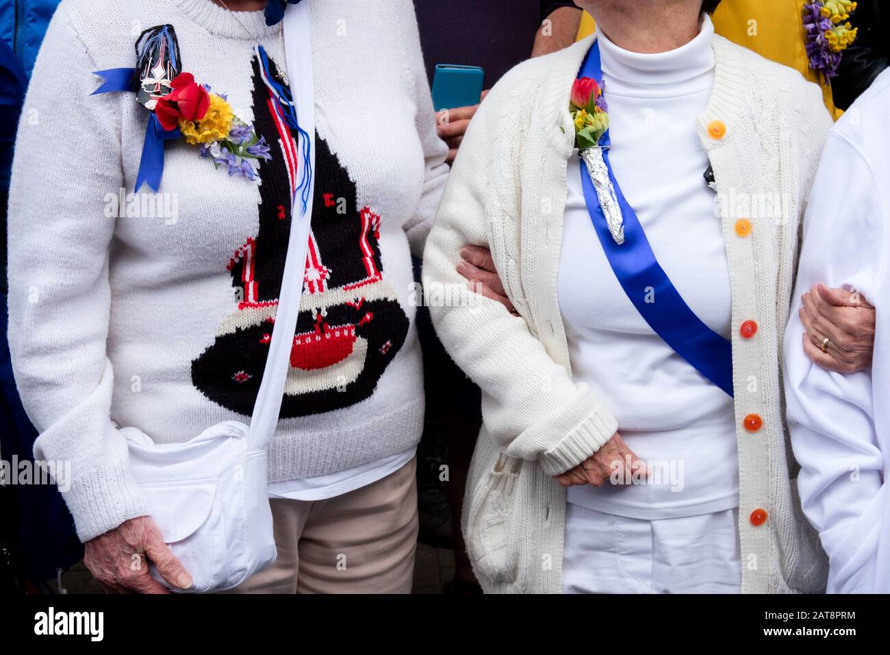People wearing blue ribbons and flowers at the Obby Oss procession, Padstow, Cornwall, UK Stock Photo