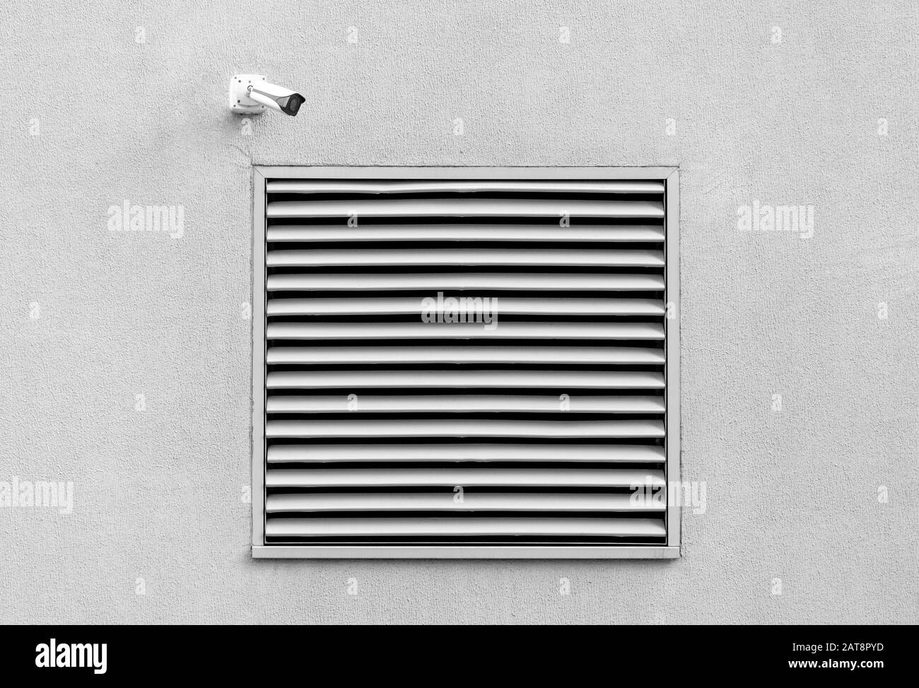 Industrial architecture detail, concrete wall and basement window with security camera, front view black and white picture Stock Photo