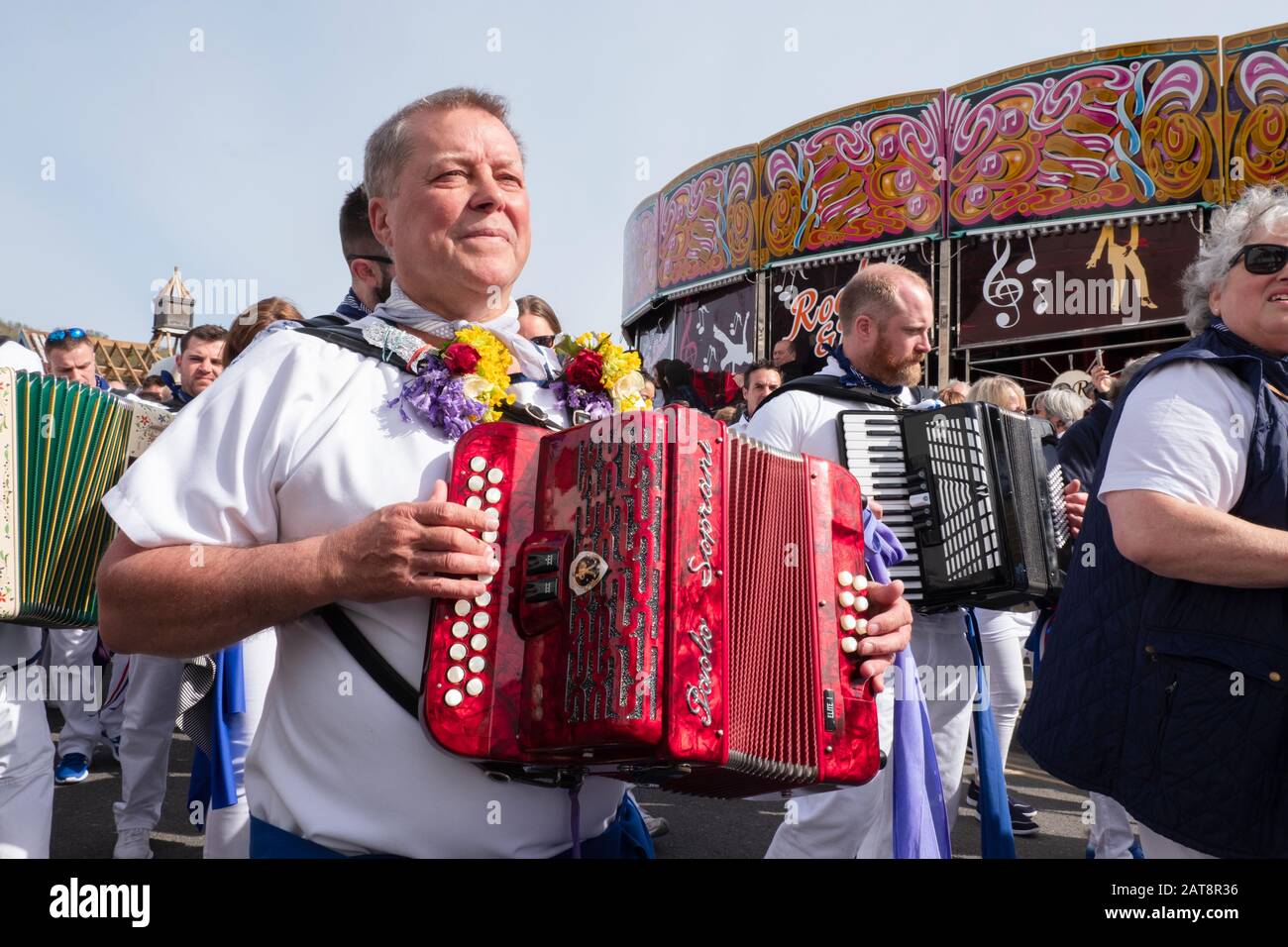 Man playing accordion and wearing flowers, Obby Oss procession, Padstow, Cornwall, UK Stock Photo