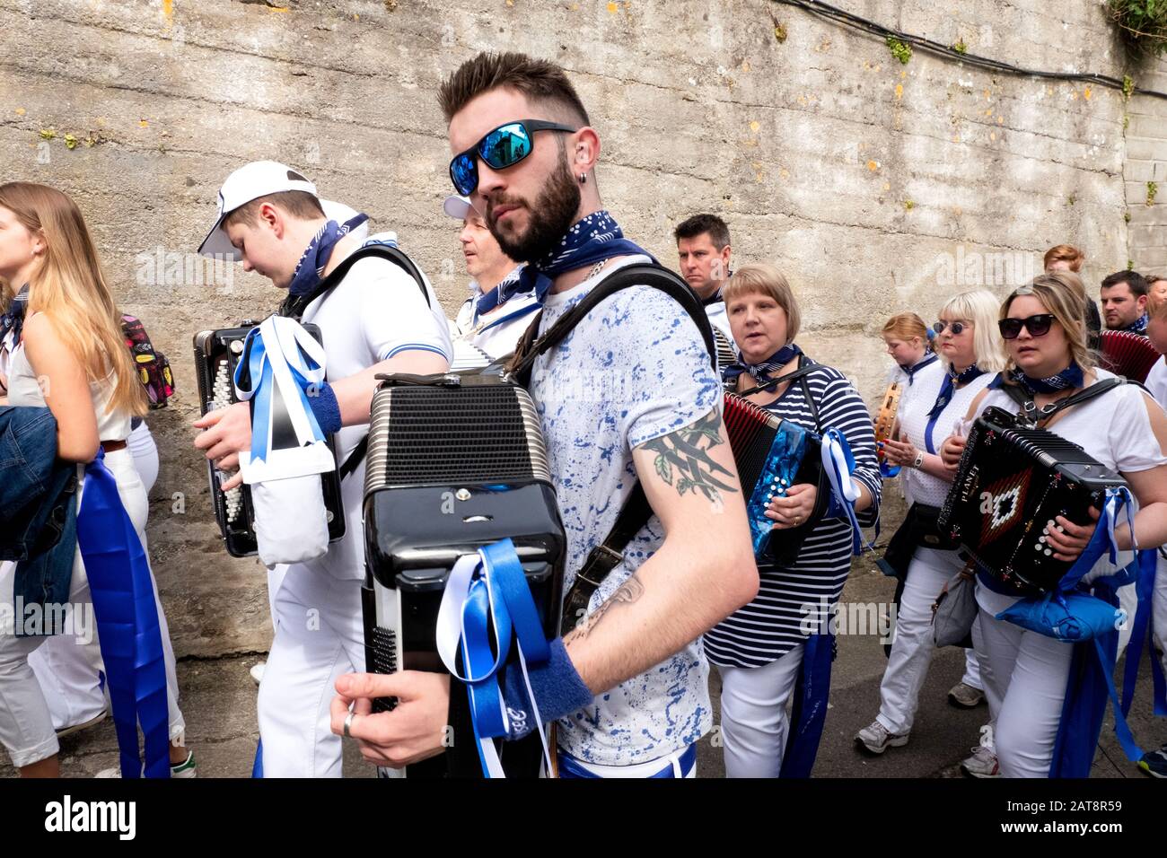 Man playing accordion and wearing blue ribbons, Obby Oss procession, Padstow, Cornwall, UK Stock Photo