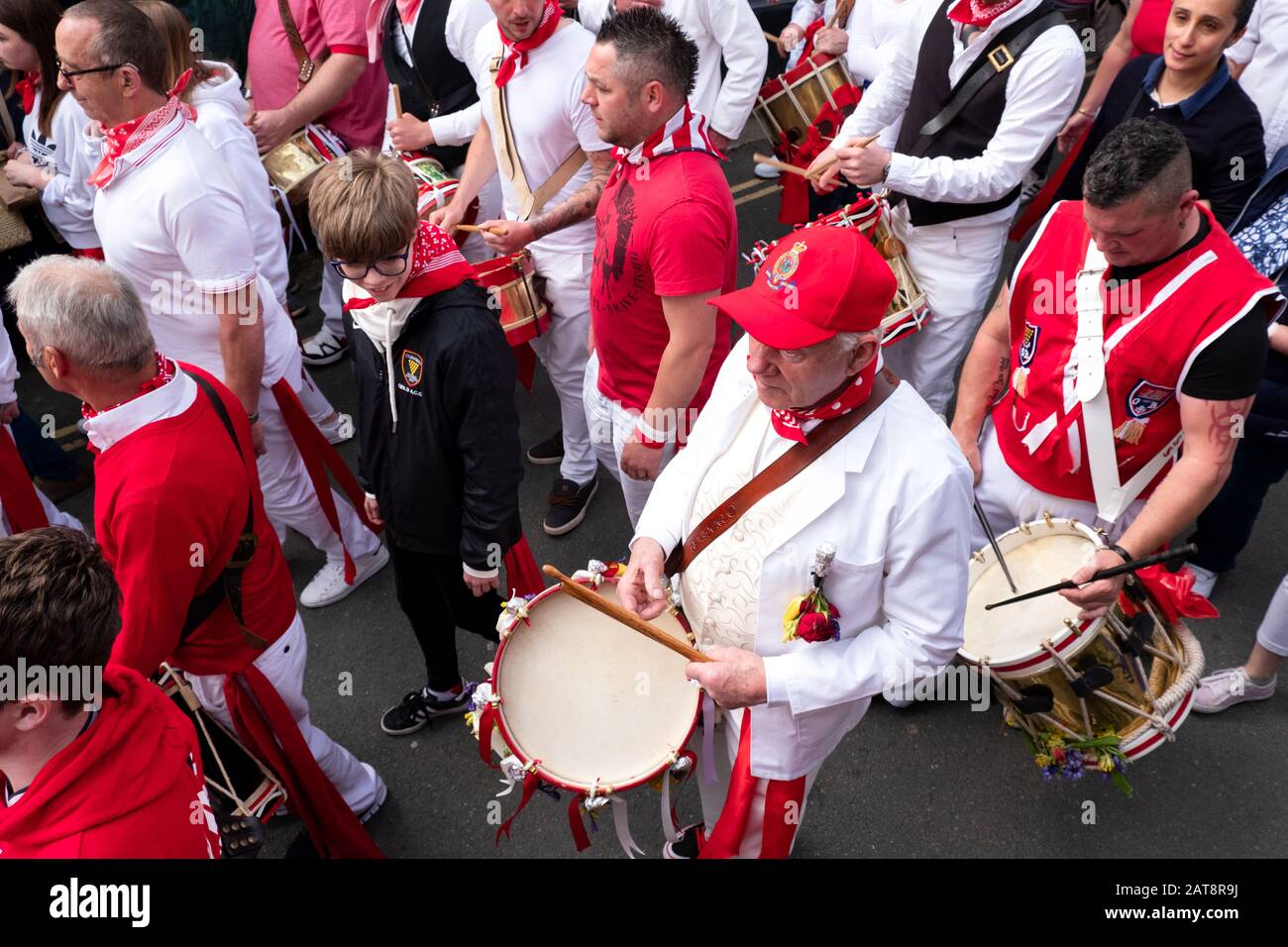Drummers playing drums and following the red ribbon Obby Oss procession, Padstow, Cornwall, UK Stock Photo