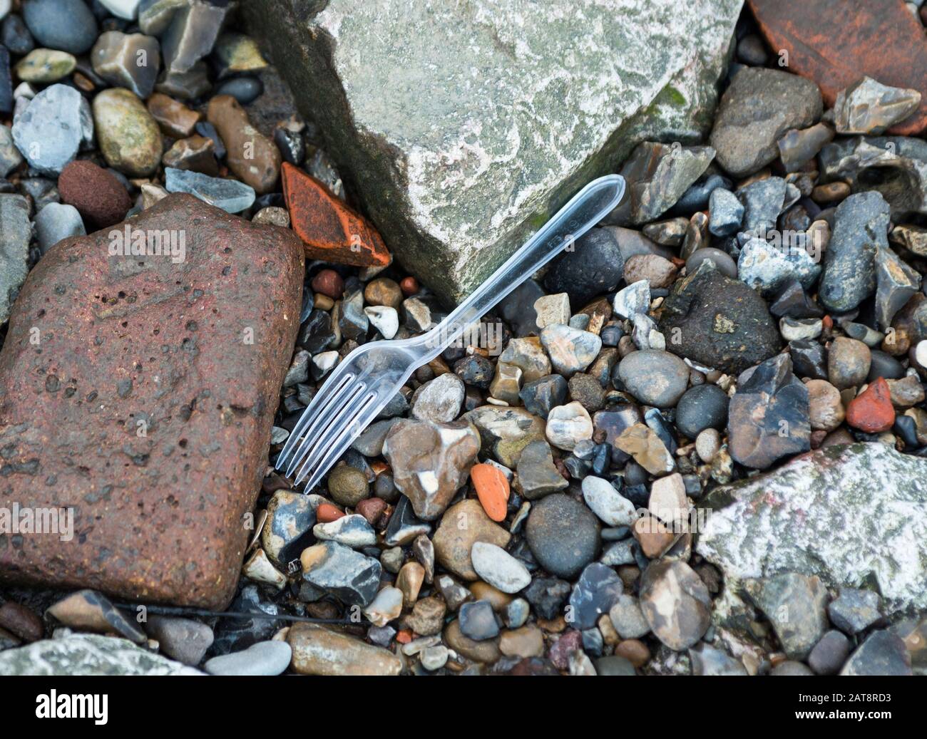A piece of single use plastic cutlery pollution washed up on a beach of