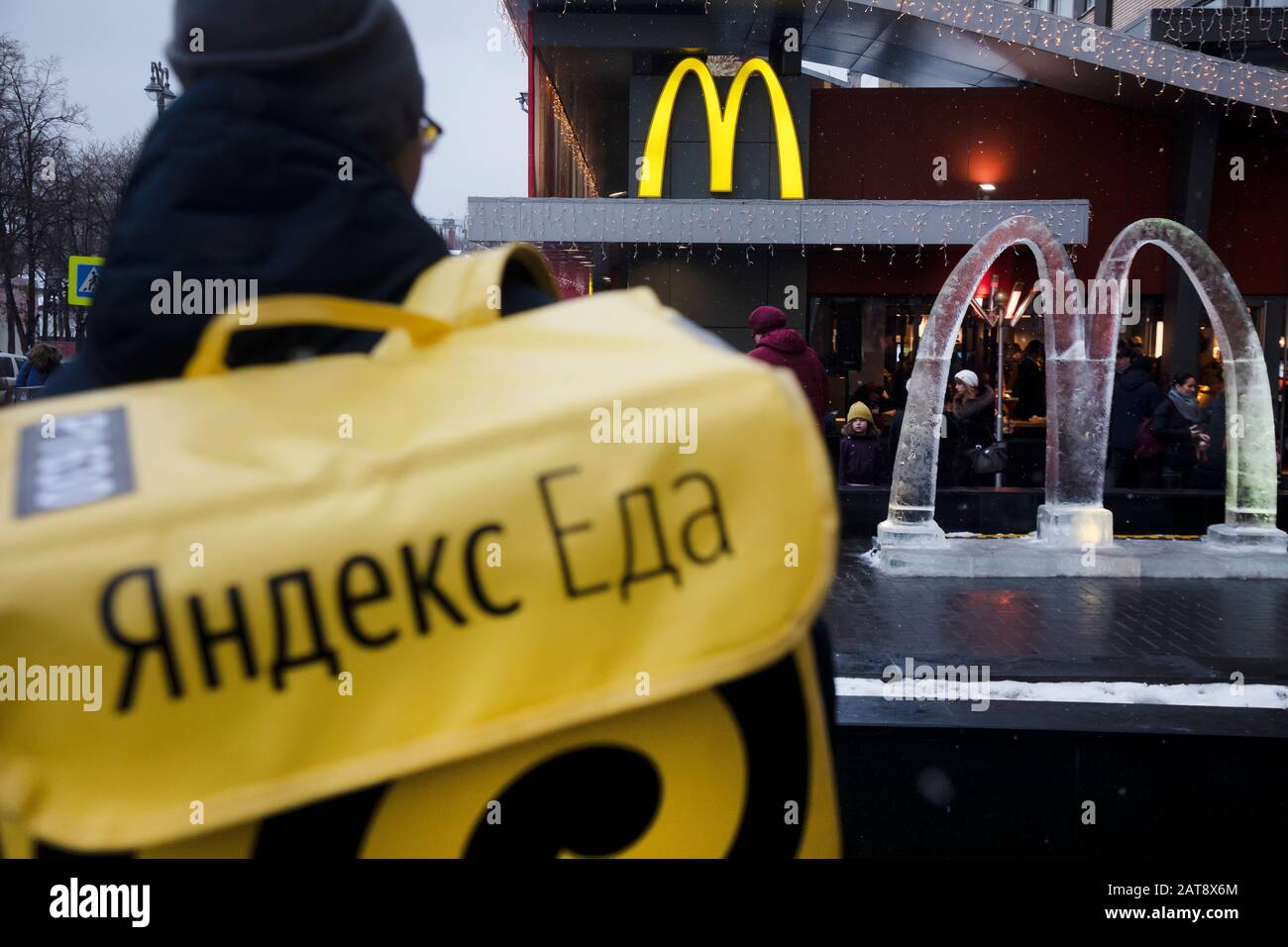 Moscow, Russia. 31st of January, 2020 A courier of food delivery company 'Yandex Eda' at the entrance to the McDonald's restaurant on Pushkin square in central Moscow, Russia Stock Photo