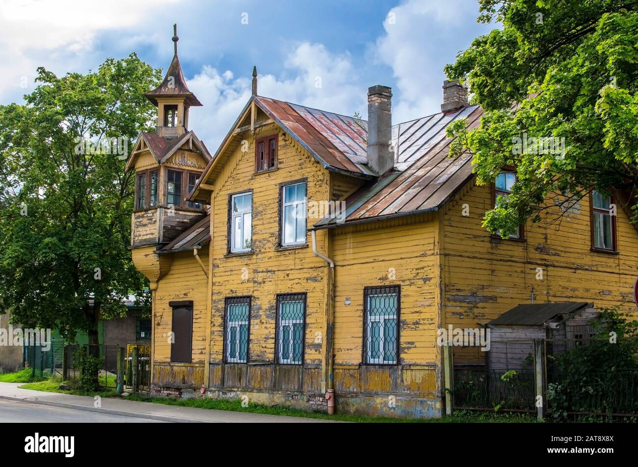 Old wooden yellow house with small tower during sunny day in summer in