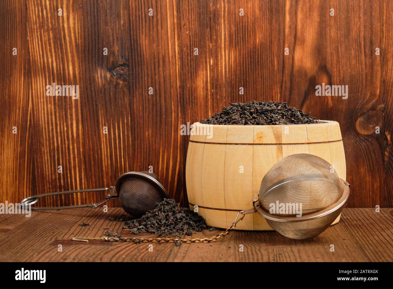 Black tea in barrel, pile of tea on wooden background and two tea  strainers. Concept of a tea shop Stock Photo - Alamy