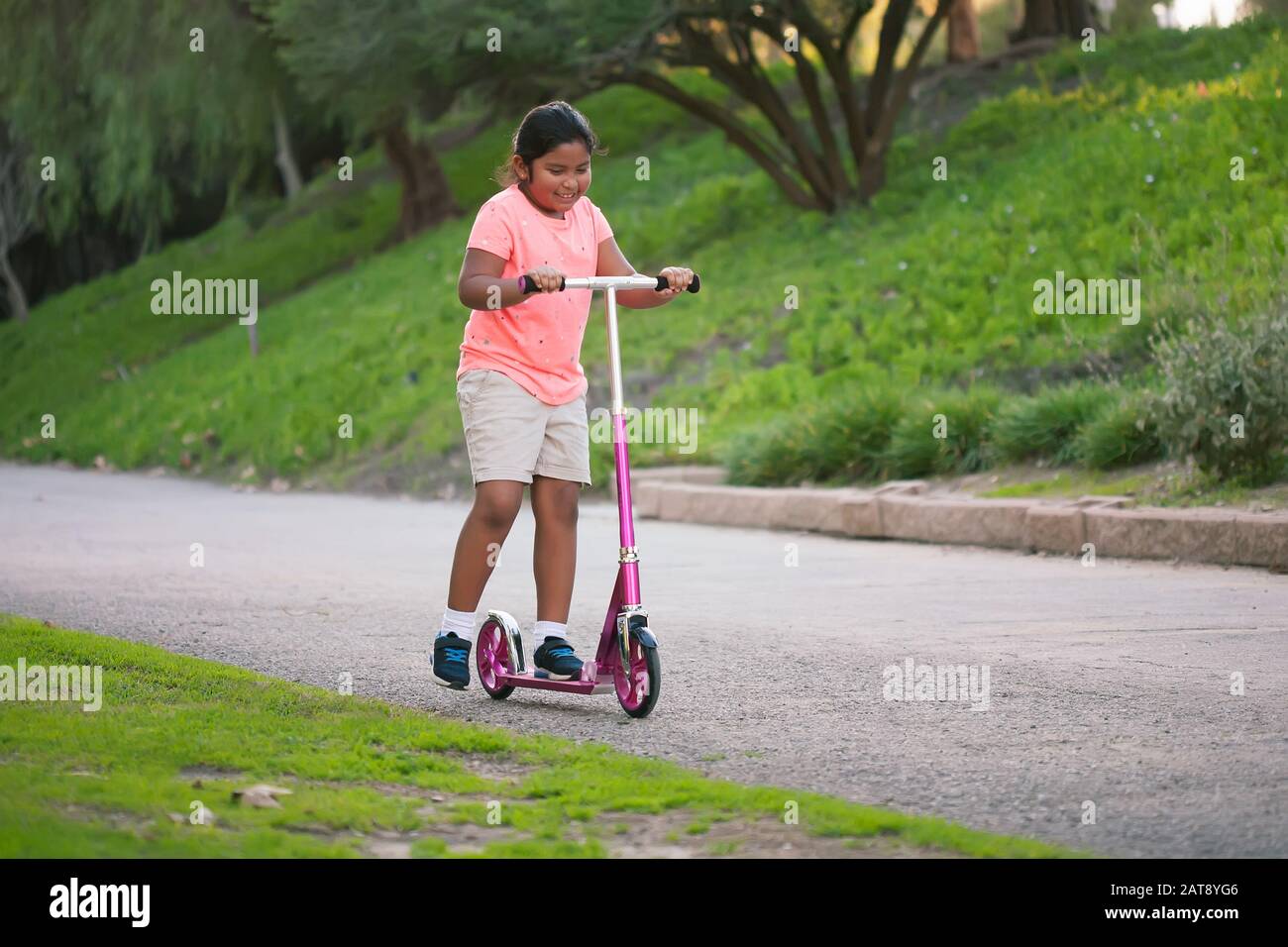 A young girl riding a pink scooter in a narrow street Stock Photo Alamy