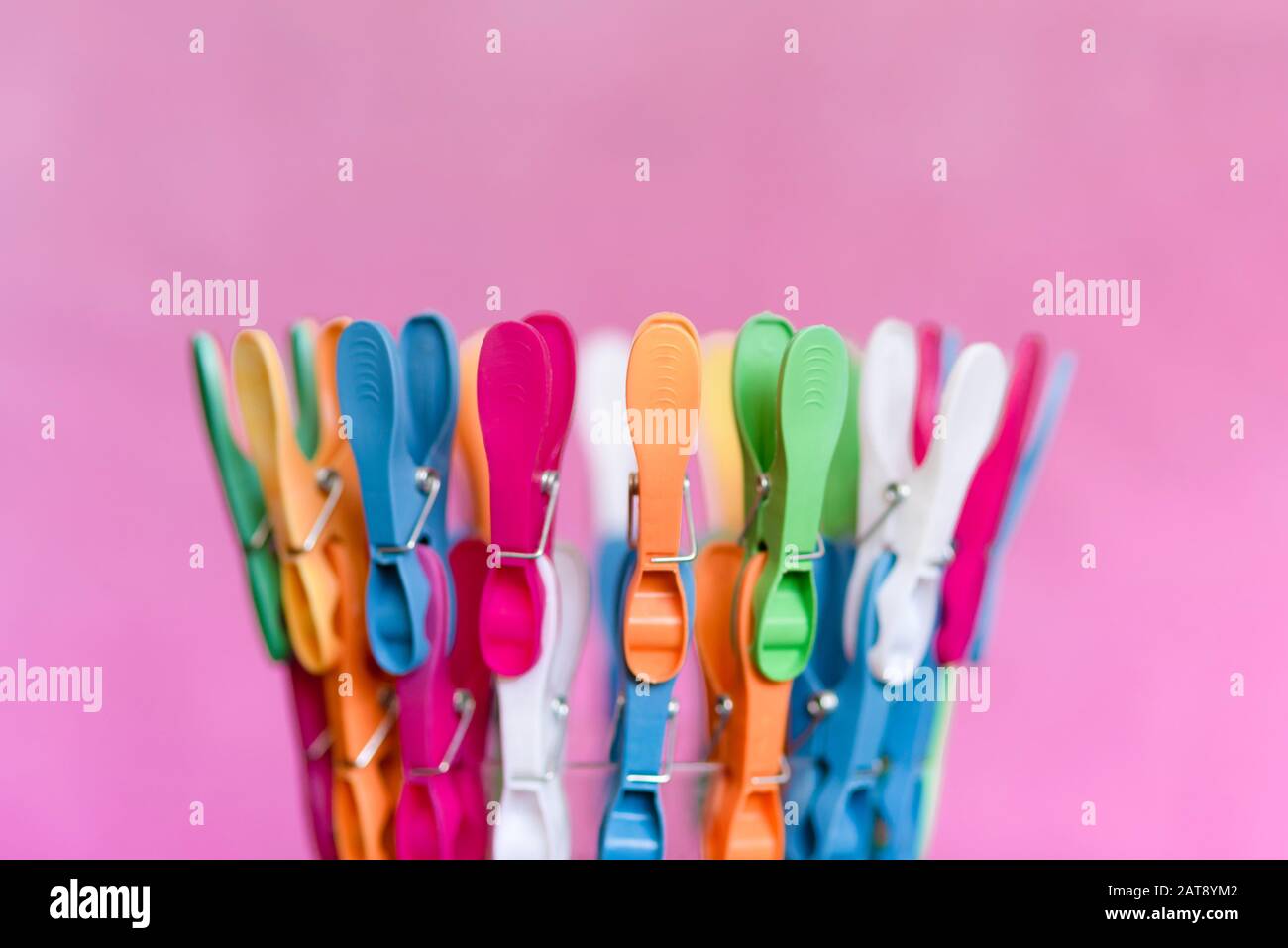 Multicolored clips for clothes, on pink background Stock Photo