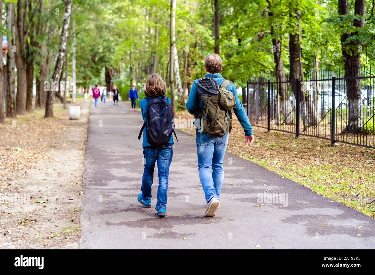 Father and son go for a walk with large backpacks and rackets.  Stock Photo