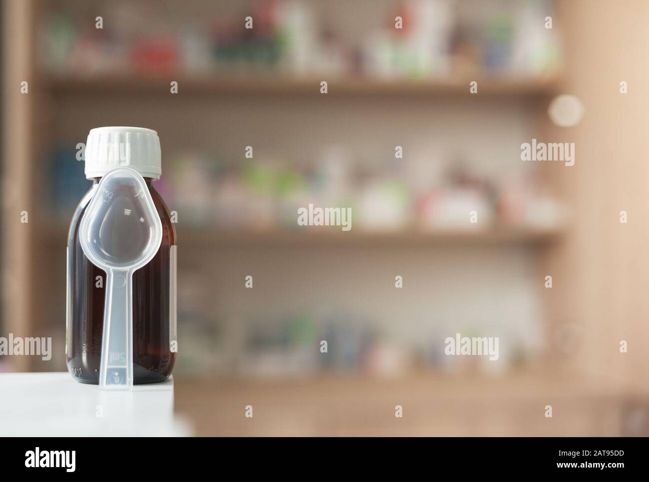 medicine in a dark glass bottle with a measuring spoon against the background of other drugs in