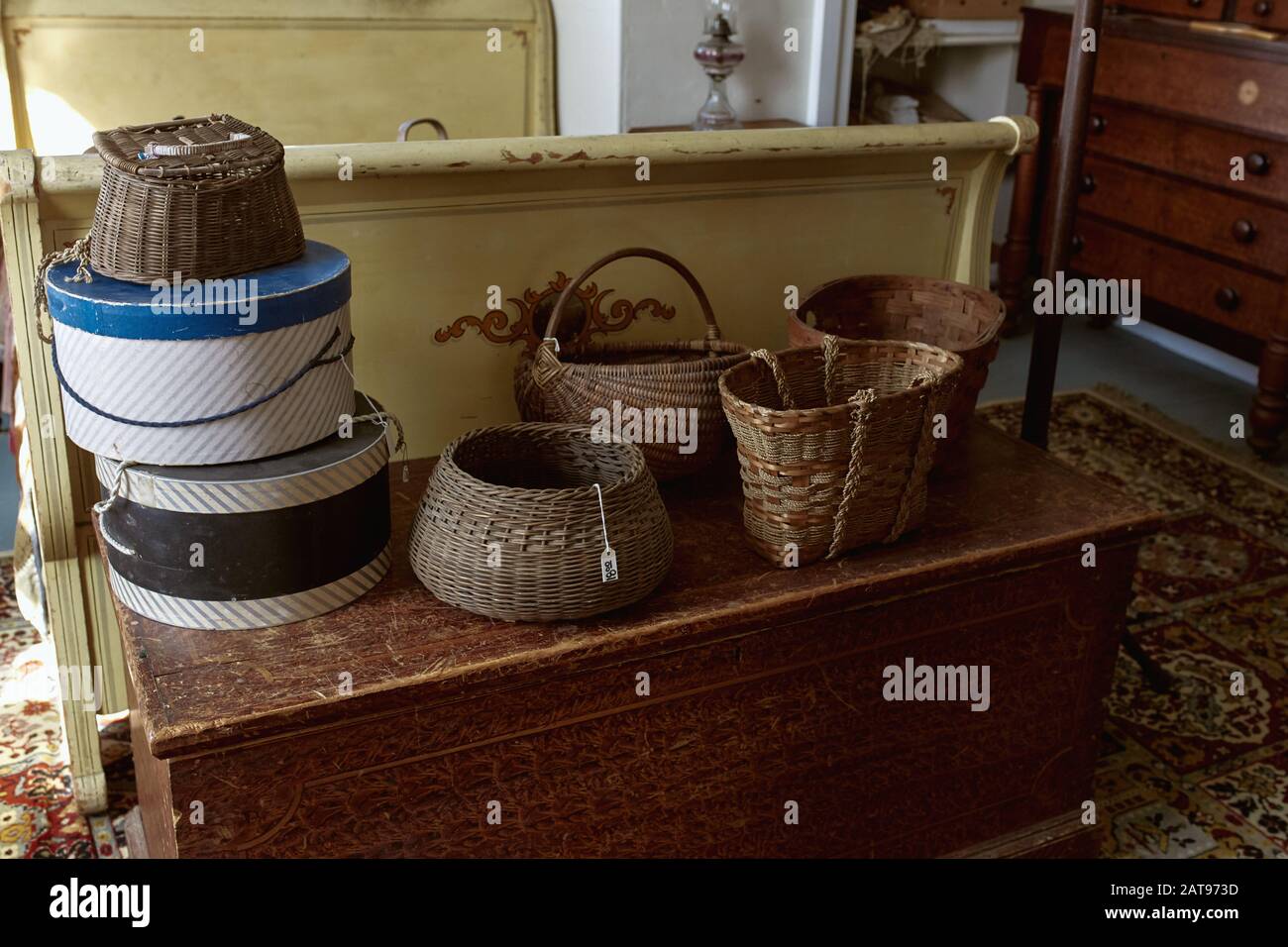 Vintage wooden bed and trunk decorated with wicker baskets at an