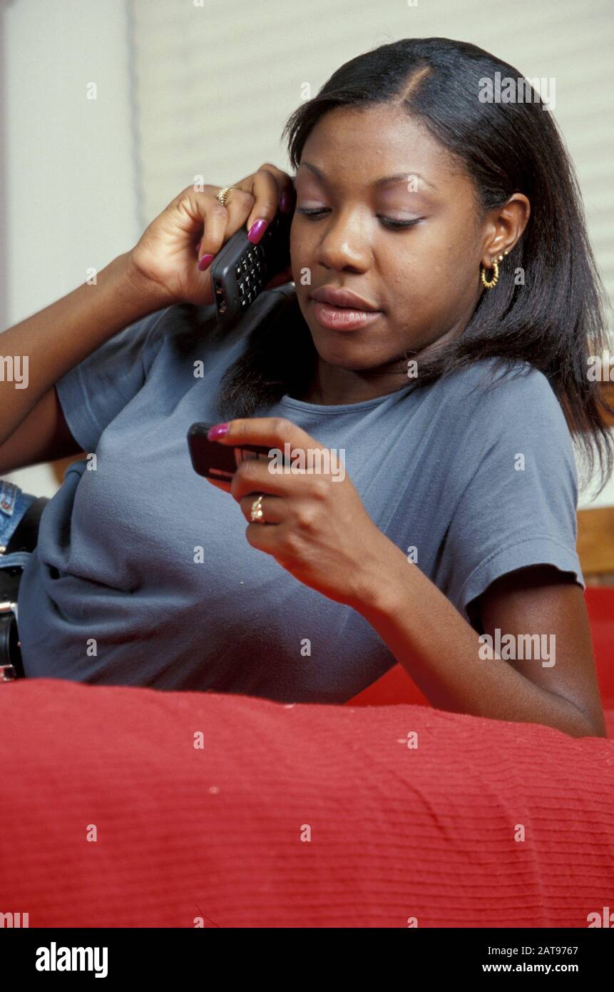 Austin, Texas: Eighteen (18) year old African-American girl talking on cellular phone while checking her pager. MR ©Bob Daemmrich Stock Photo