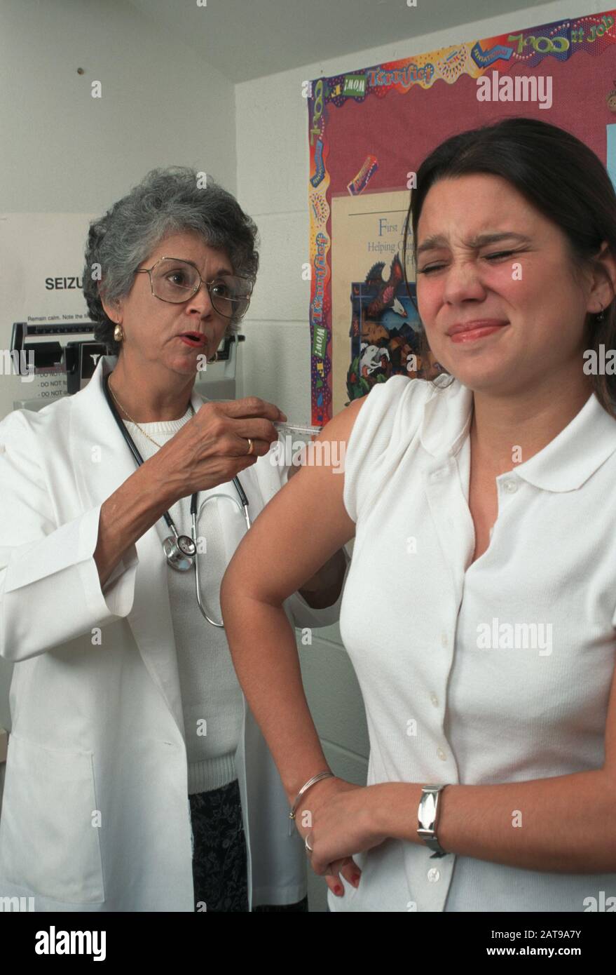 Hispanic teen girl is given an immunization shot by female Hispanic doctor.  ©Bob Daemmrich Stock Photo