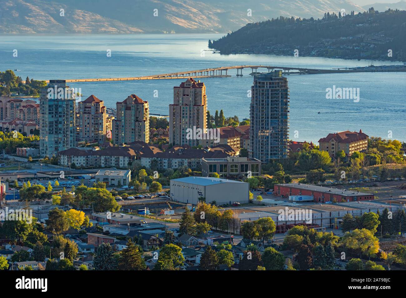 a view of the Kelowna British Columbia skyline and Okanagan Lake with the R W Bennett Bridge in the background from Knox Mountain at sunset Stock Photo