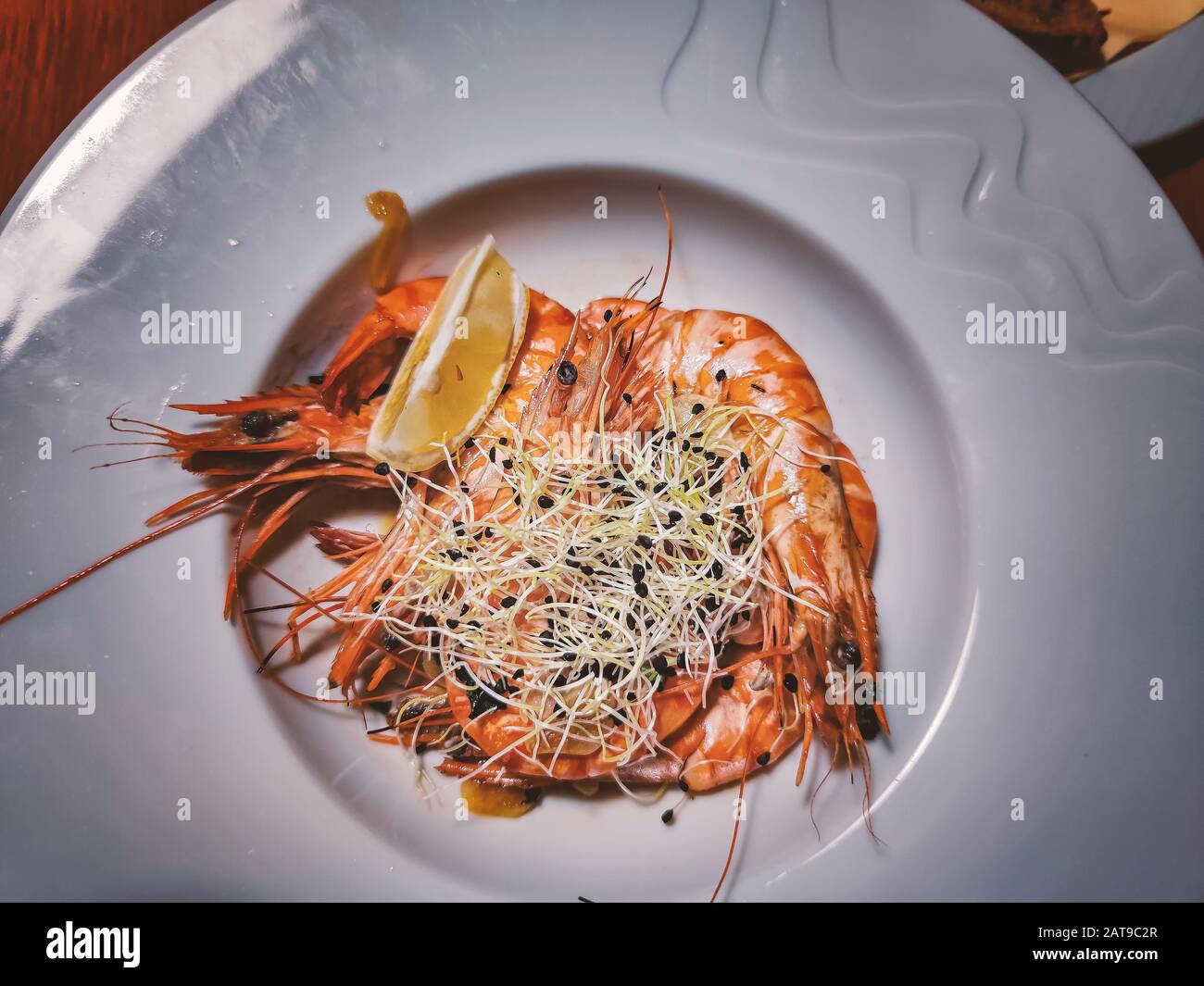 Grilled large tiger prawns with garlic, lemon and herbs on a large white plate. Stock Photo