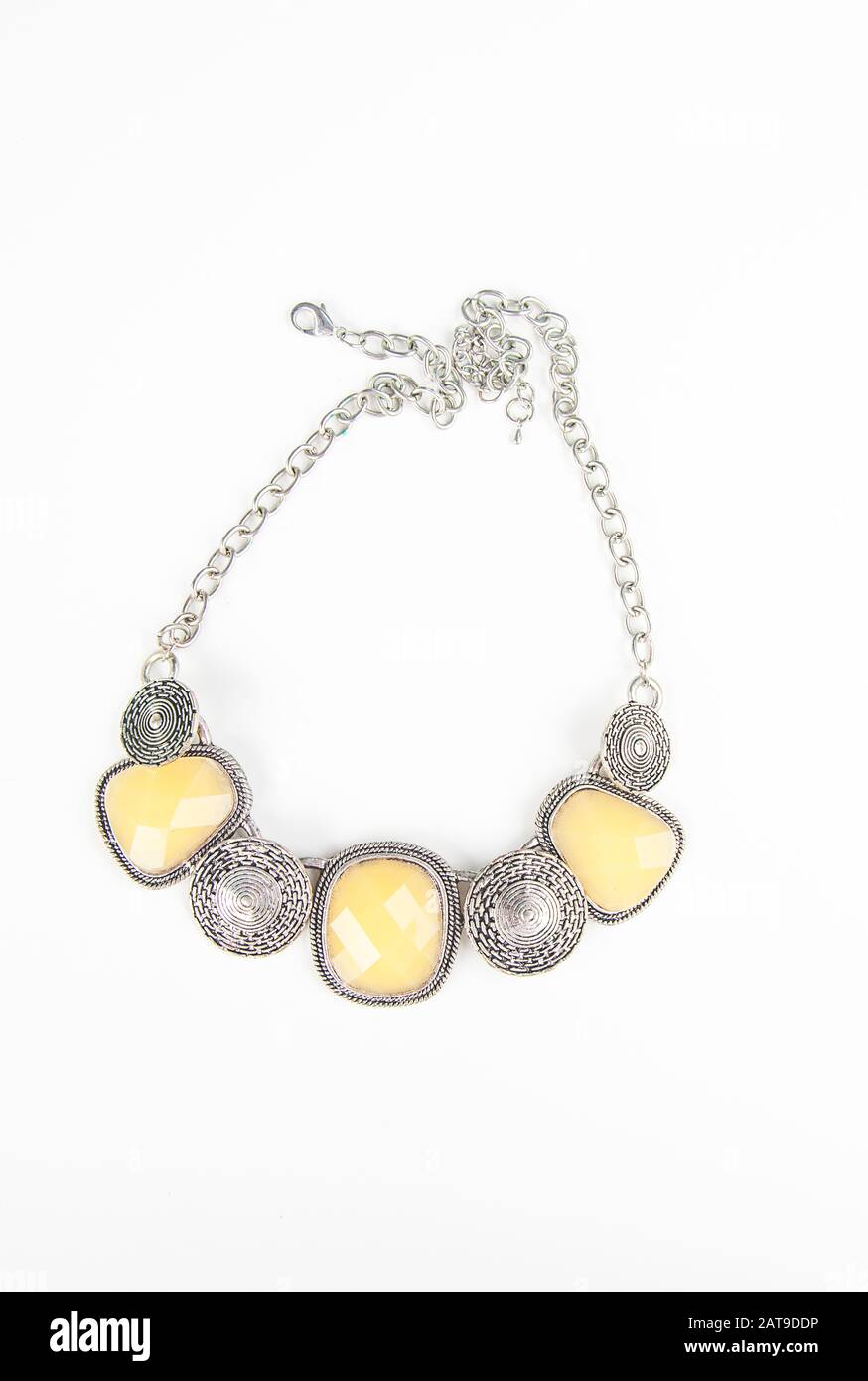 Chunky fashion statement necklace jewelry in silver and light yellow on a chain.  Fashion accessory is isolated on a light background. Stock Photo