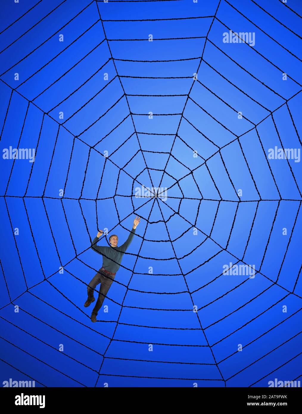 Man climbs upward and across a black web on blue background. Stock Photo