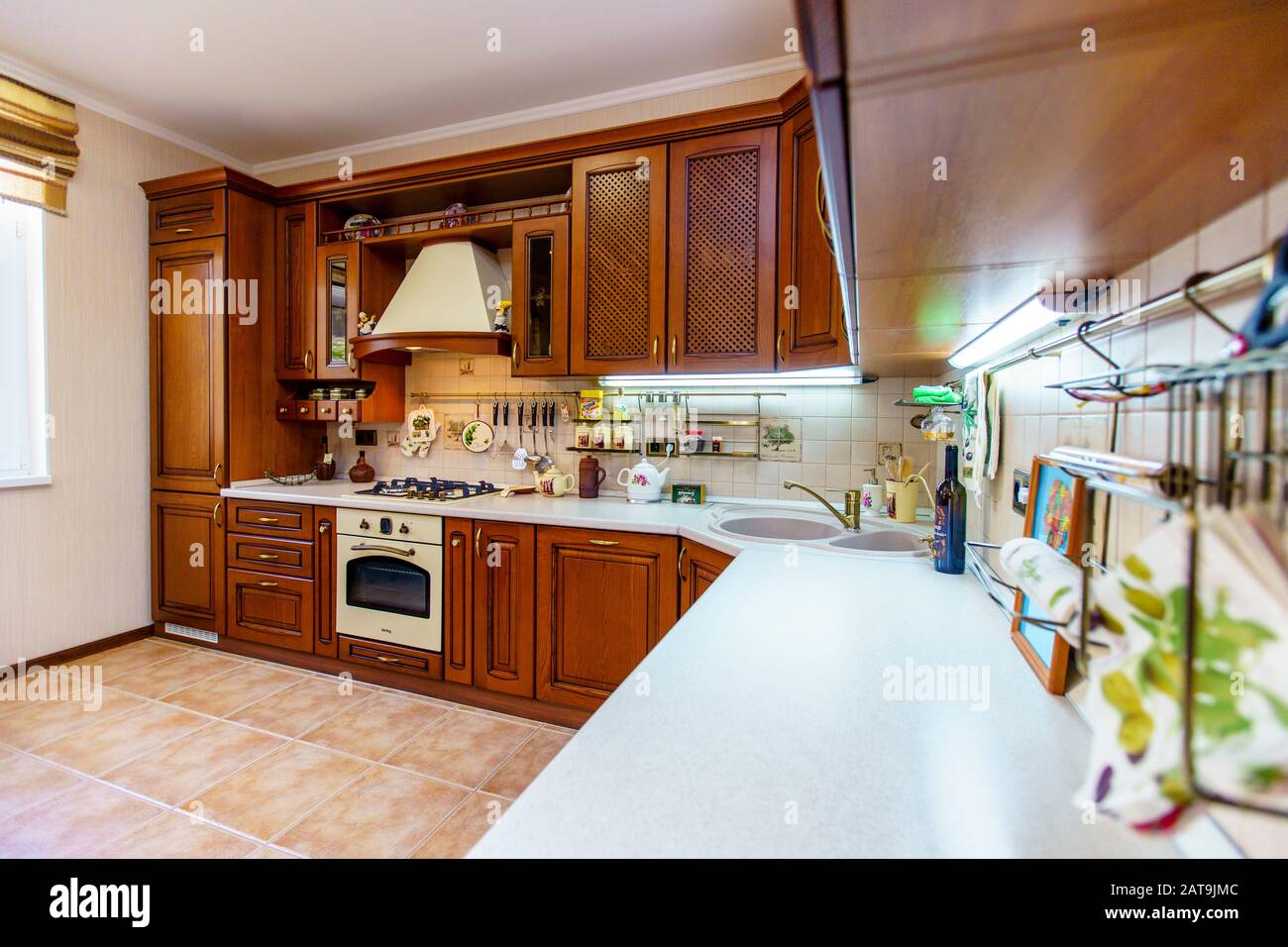 Warm and inviting kitchen with large kitchen island, cherrywood cabinets, gold granite counter tops and modern stainless steel refrigerator. Modern ki Stock Photo