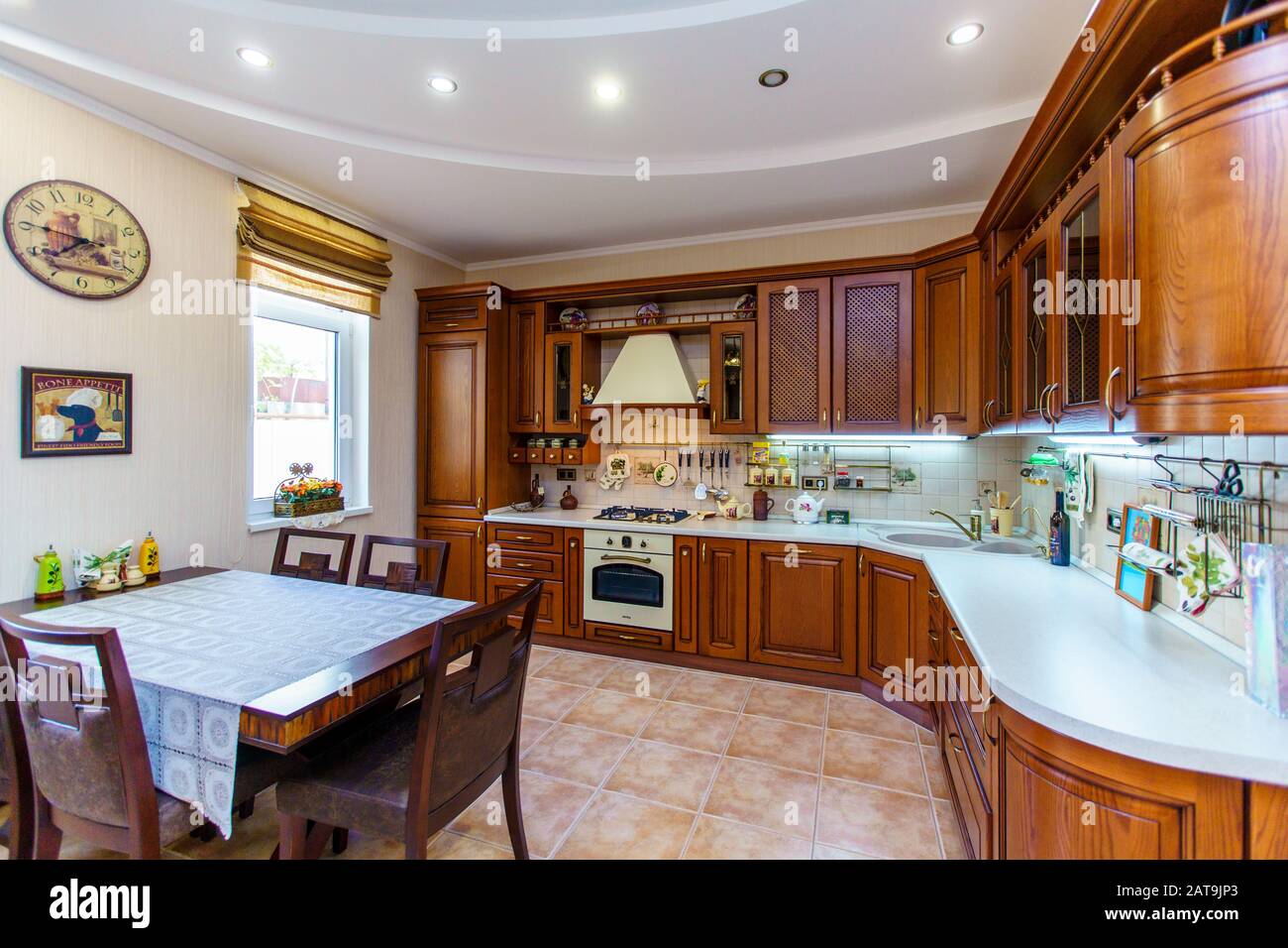 Warm and inviting kitchen with large kitchen island, cherrywood cabinets, gold granite counter tops and modern stainless steel refrigerator. Modern ki Stock Photo