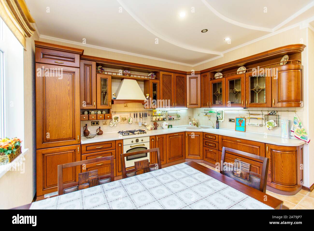 Warm and inviting kitchen with large kitchen island, cherrywood cabinets, gold granite counter tops and modern stainless steel refrigerator. Modern ki Stock Photo