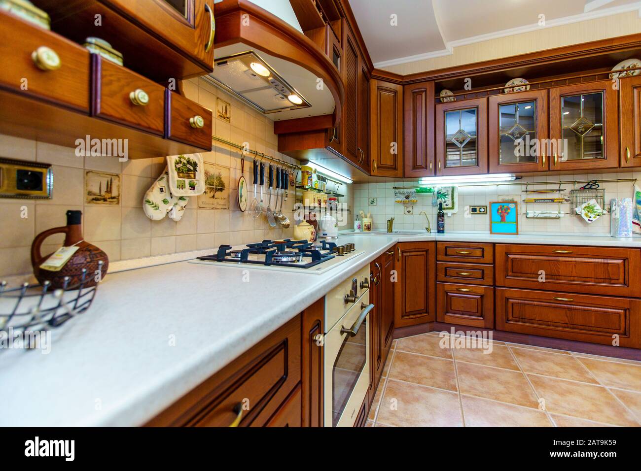 Warm and inviting kitchen with large kitchen island, cherrywood cabinets, gold granite counter tops and modern stainless steel refrigerator. Modern ki Stock Photo