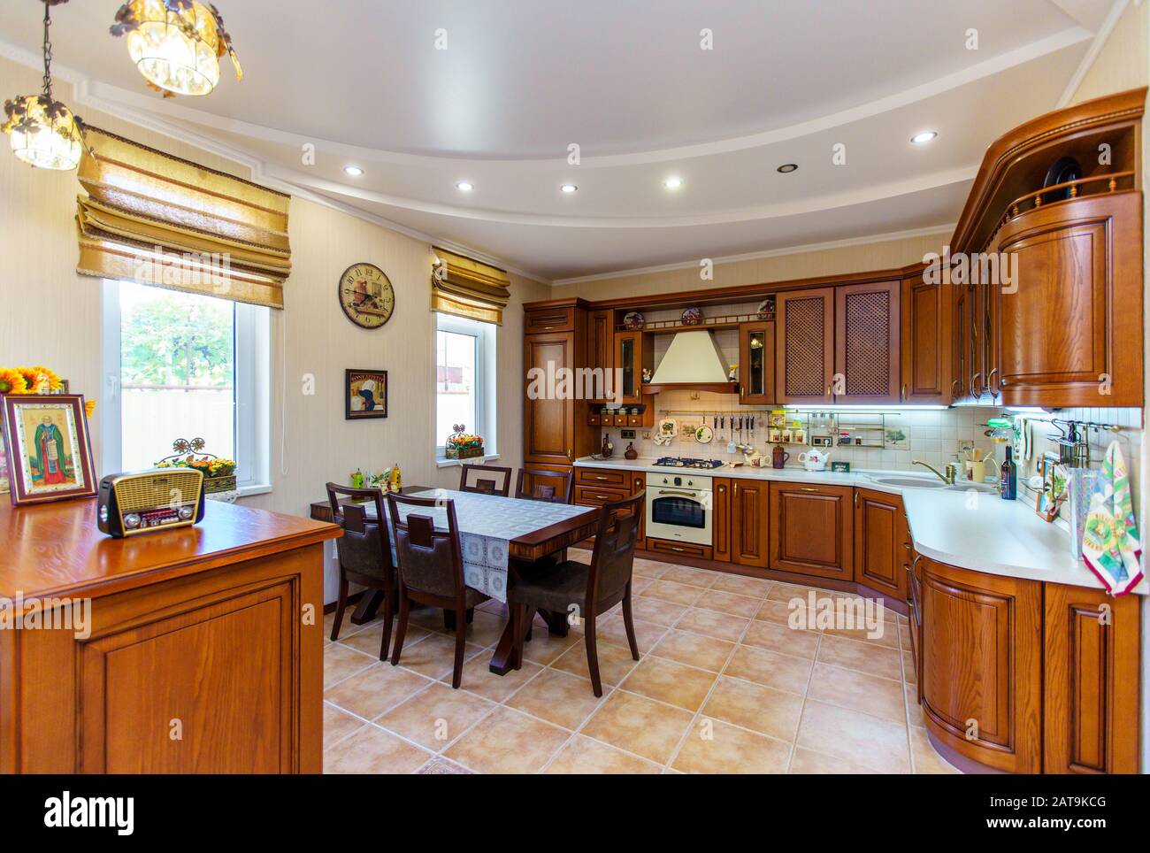 Warm and inviting kitchen with large kitchen island, cherrywood cabinets, gold granite counter tops and modern stainless steel refrigerator. Modern ki Stock Photo