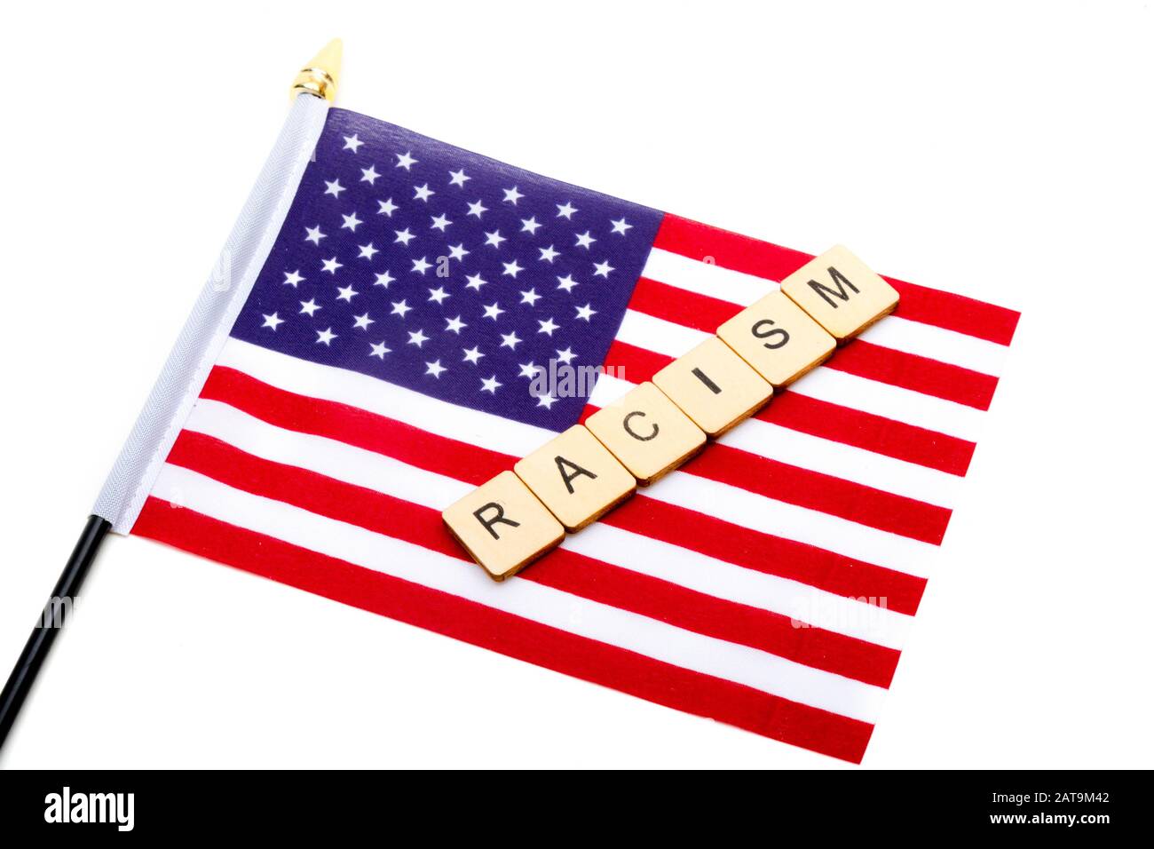 The flag of the United States isolated on a white background with a sign reading Racism Stock Photo