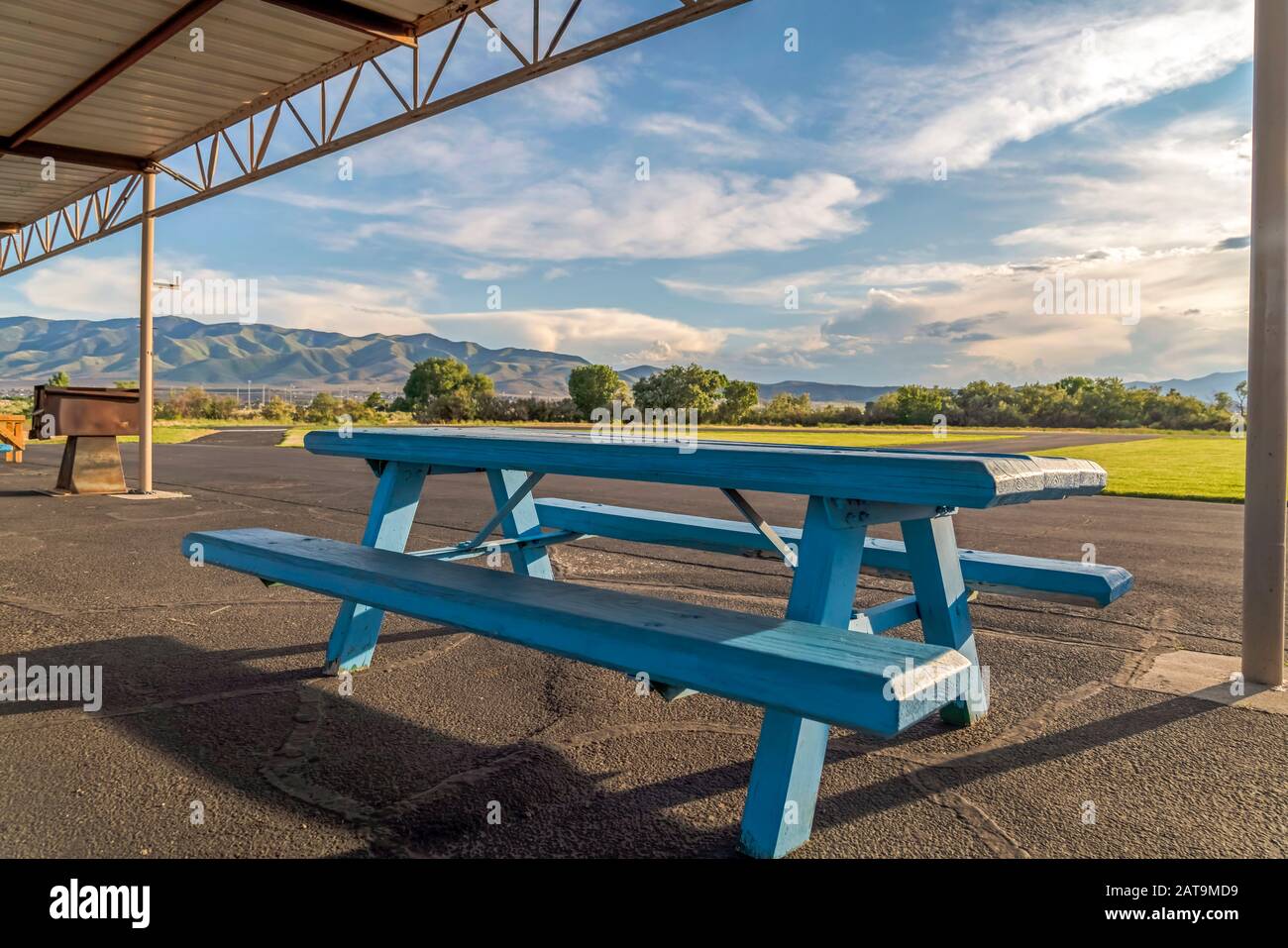Blue wood picnic table with seats under the white roof of a park ...