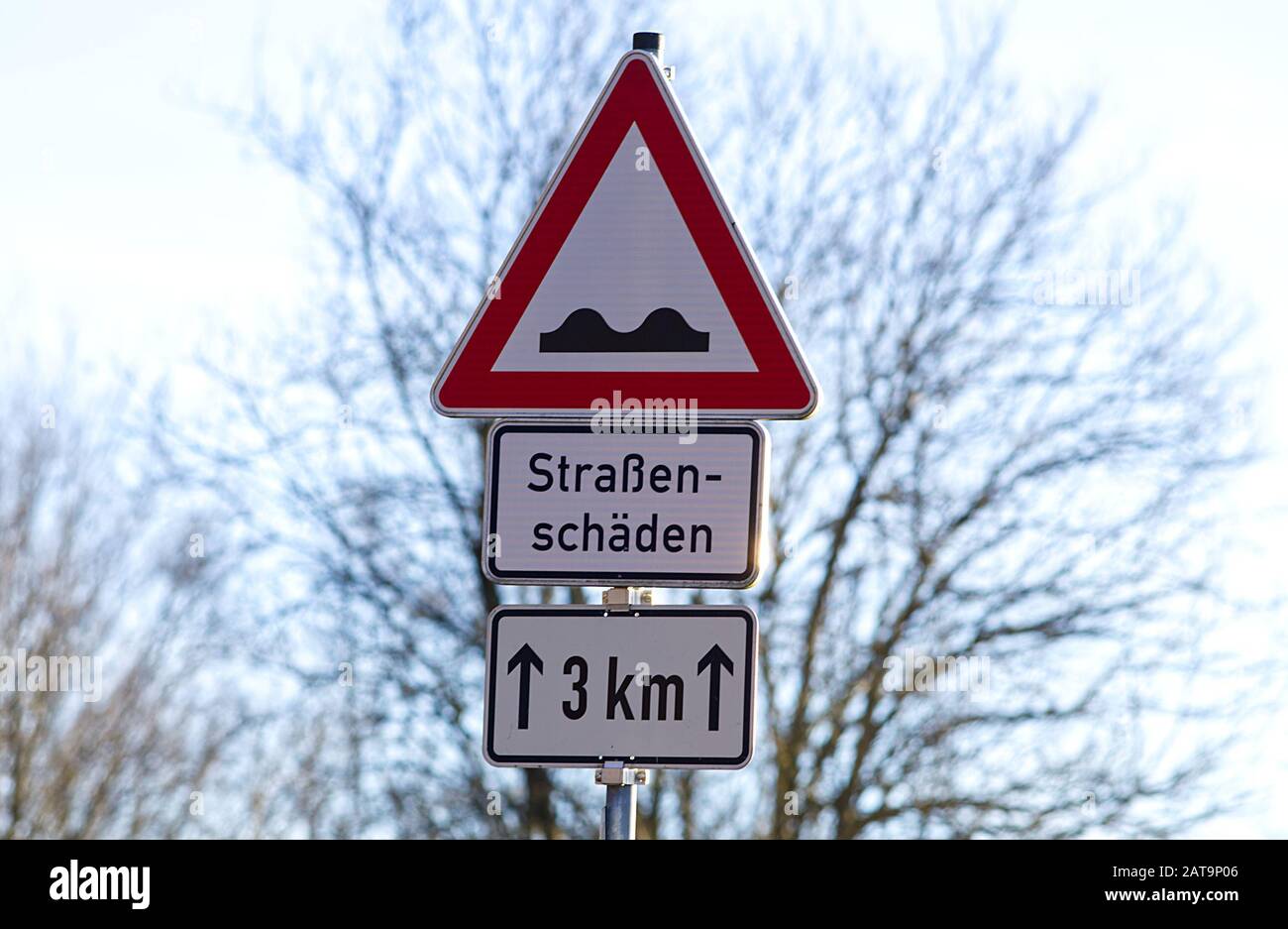 Pothole sign Uneven surfaces ahead, bumpy road. warning car driver at road damages german text translation 'road damaged' Stock Photo
